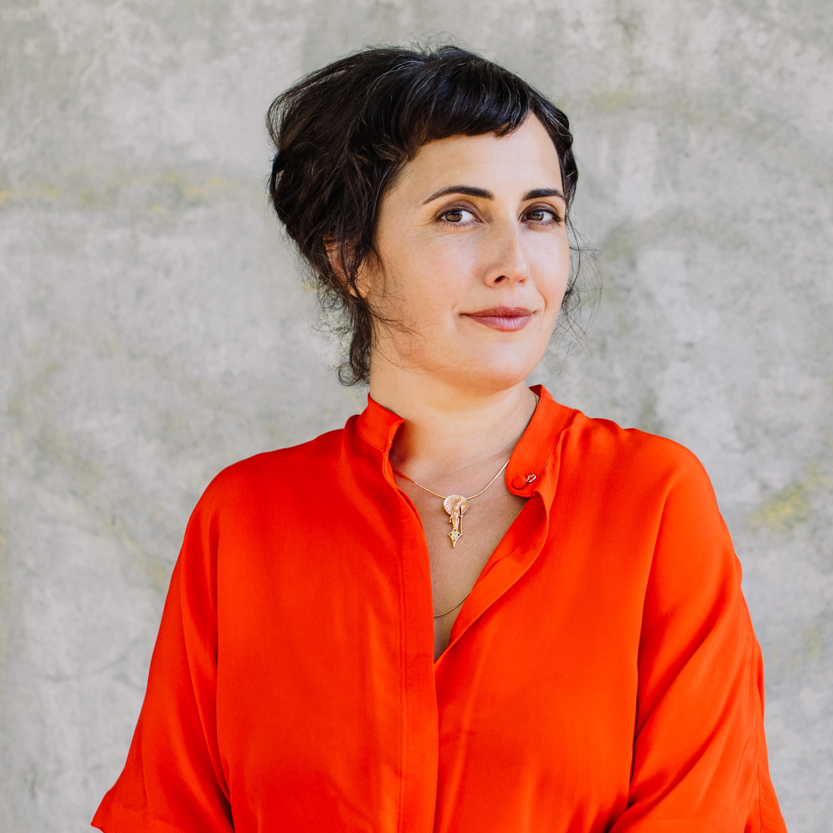 headshot of writer lauren markham in an orange shirt and cream background