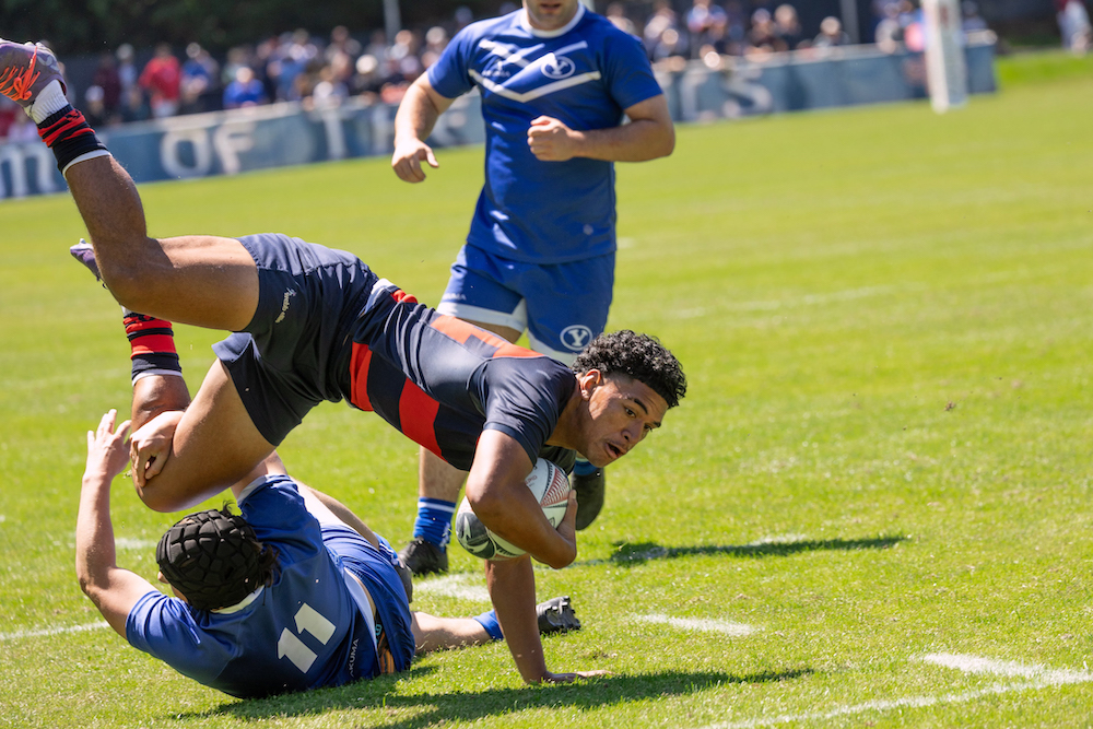 Men's rugby player Sosaia Pongi dives with the ball over a BYU defender, April 2024