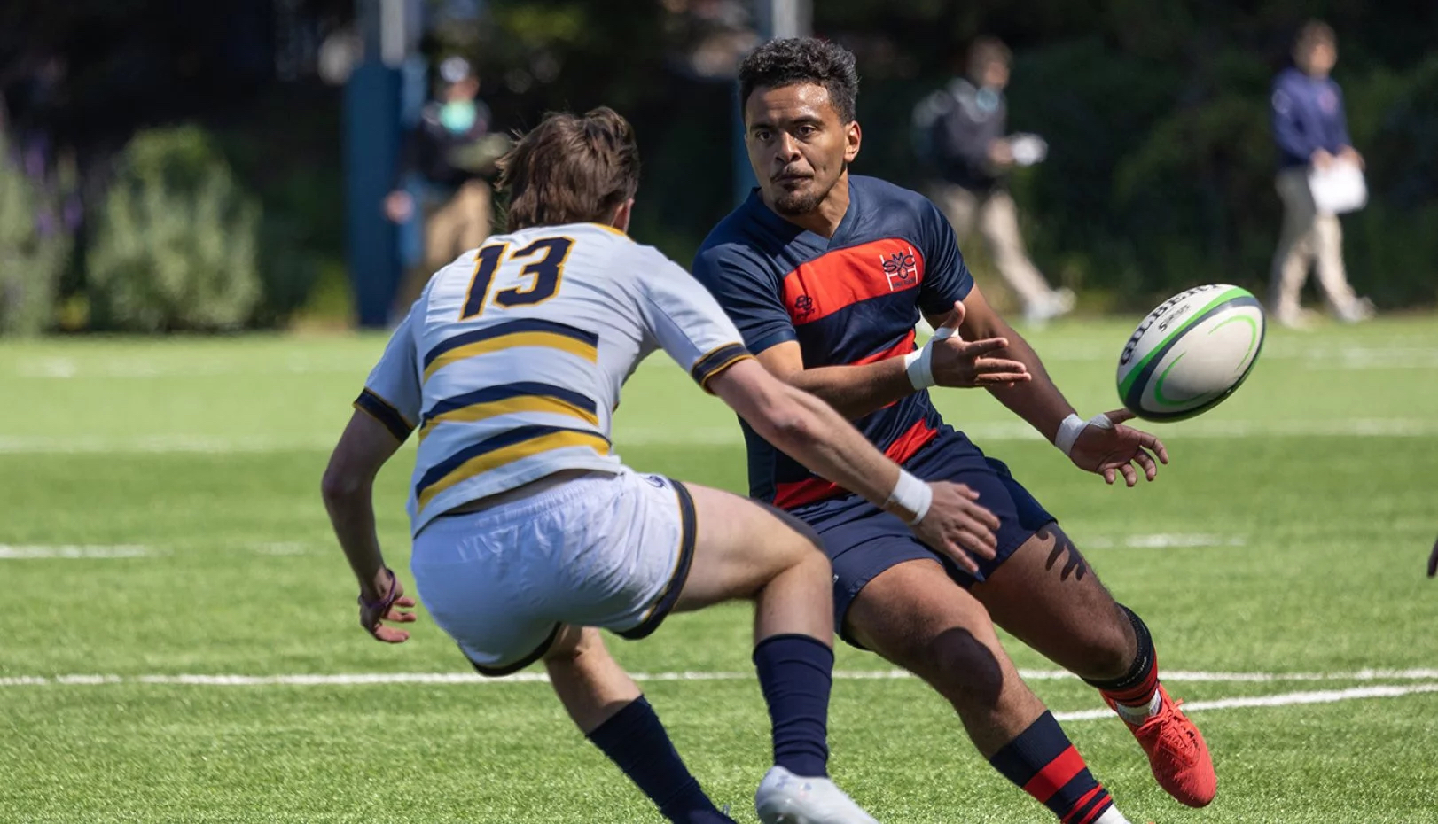 men's rugby player Inoke Waqavesi Jr. passes the ball to escape a Cal defender in spring 2023