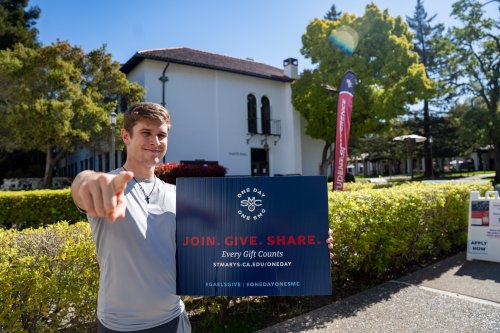A student holds a One Day One SMC sign outside on campus