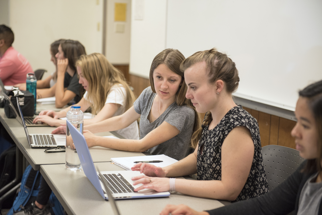 2 students in class looking at one laptop