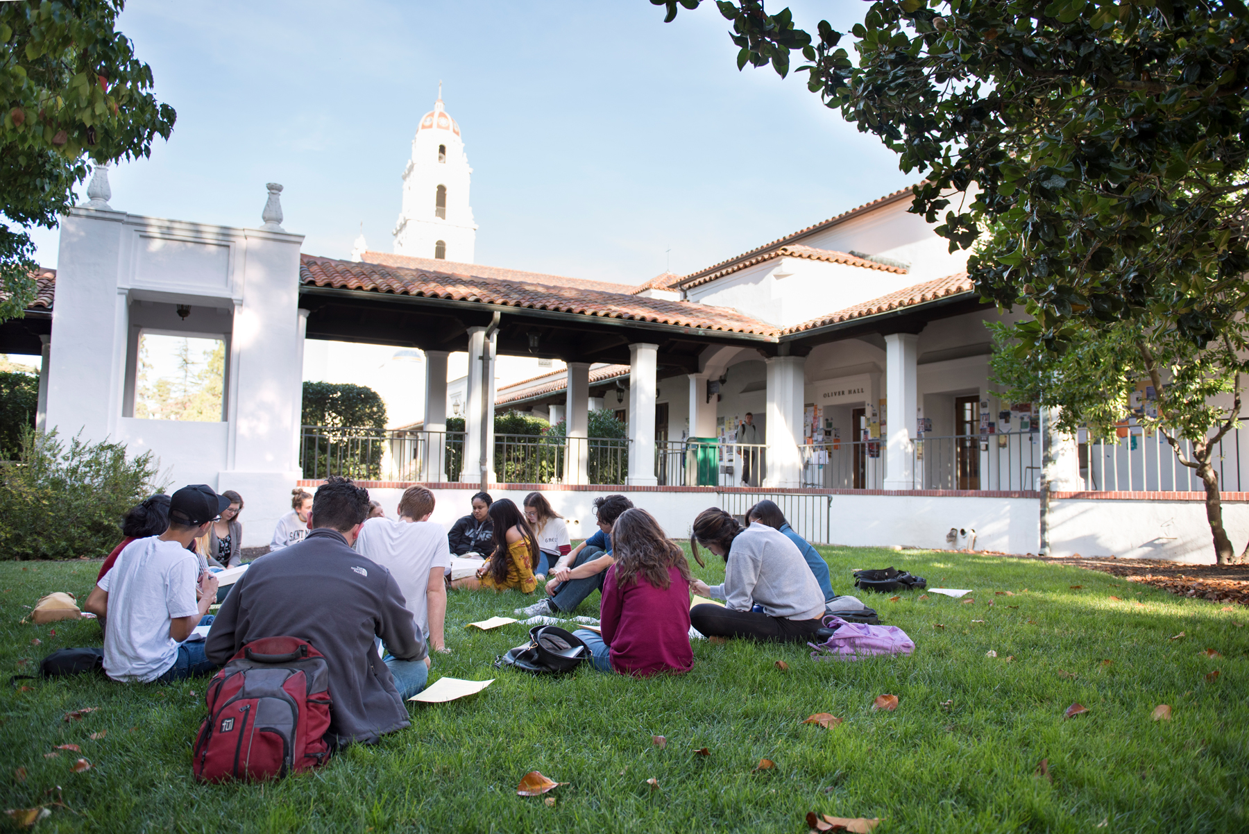 A class meeting outside on the grass with the SMC chapel in the background