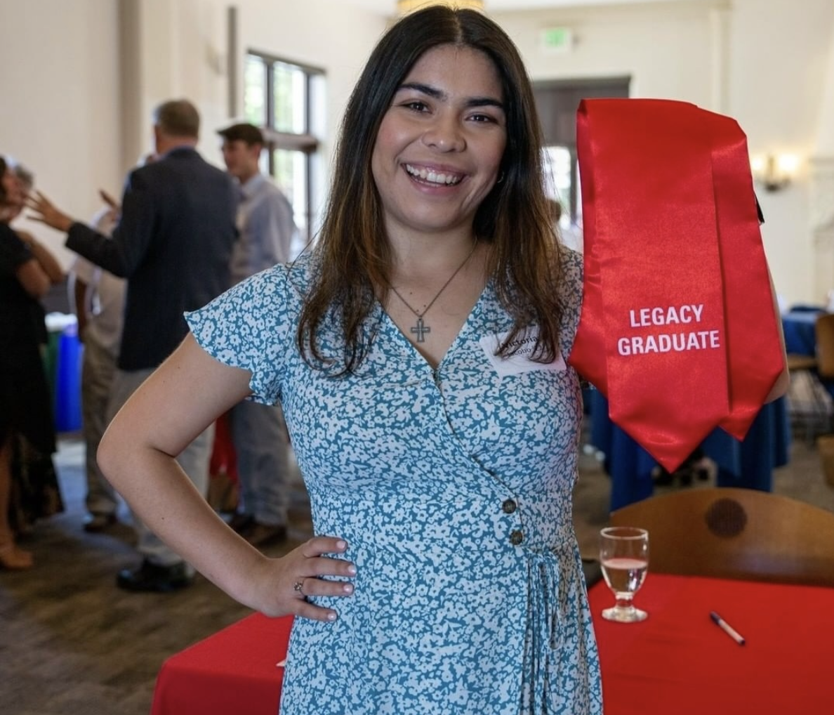 A student is posing with her stole that says "Legacy Graduate"