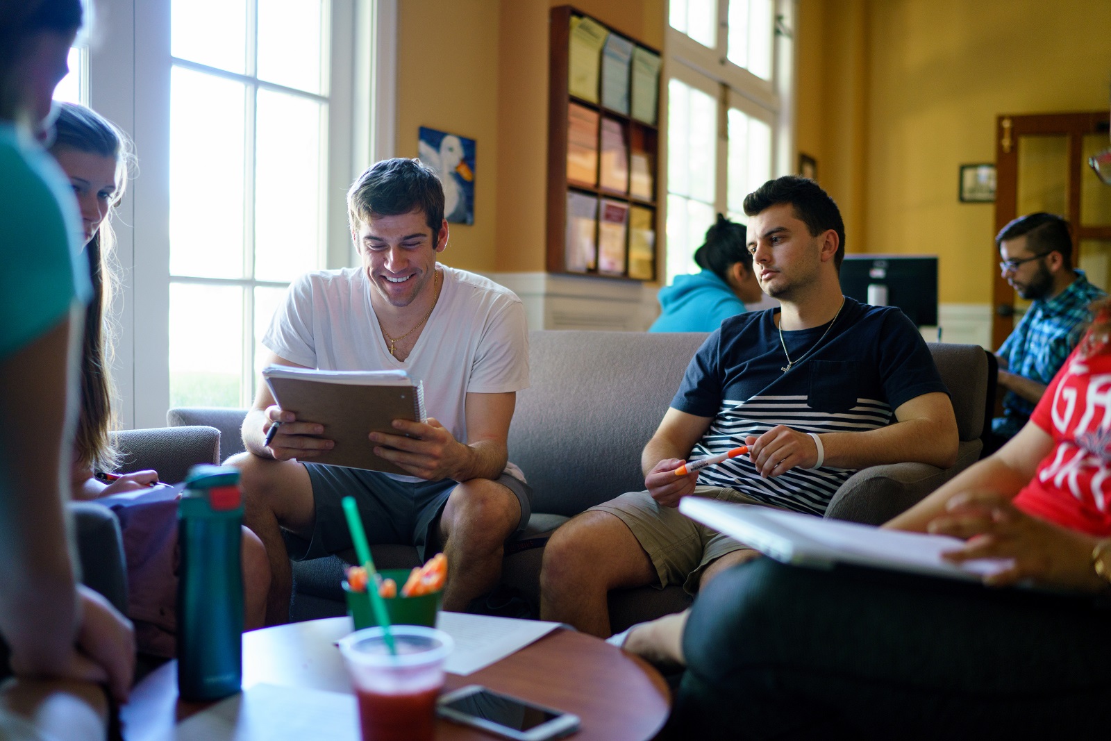 Students discussing an essay while sitting on sofas in the Writing Center.