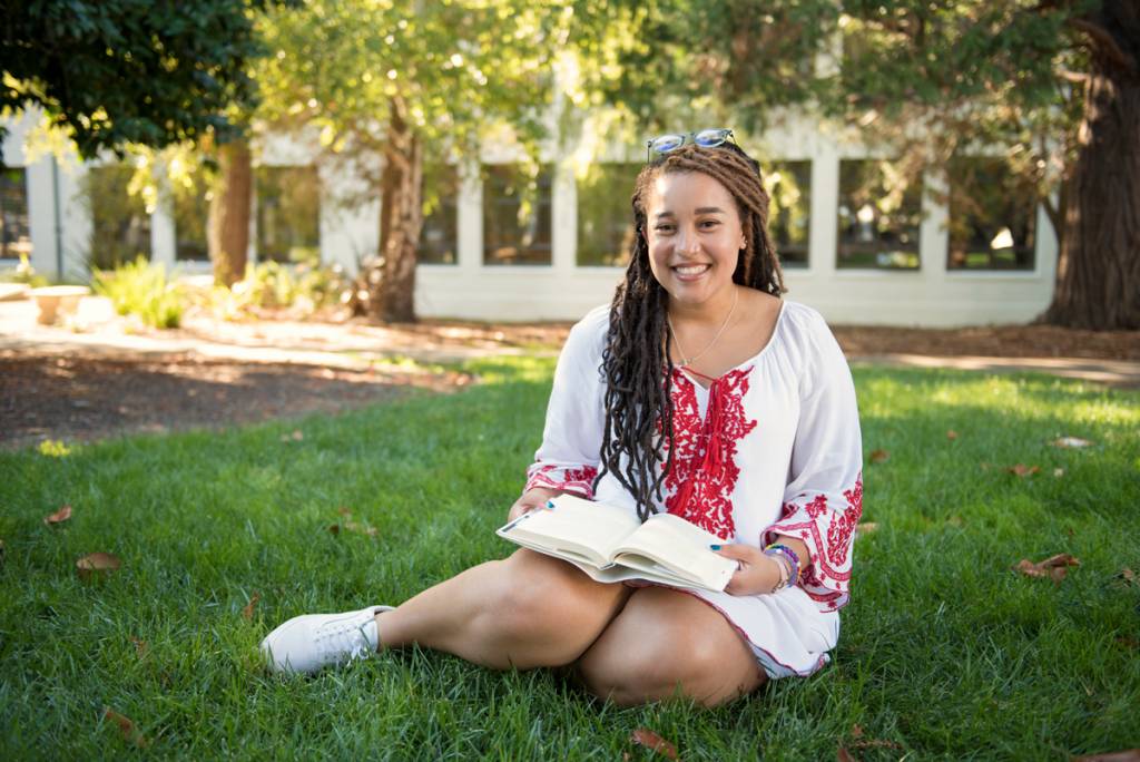 Student sitting on grass with book open
