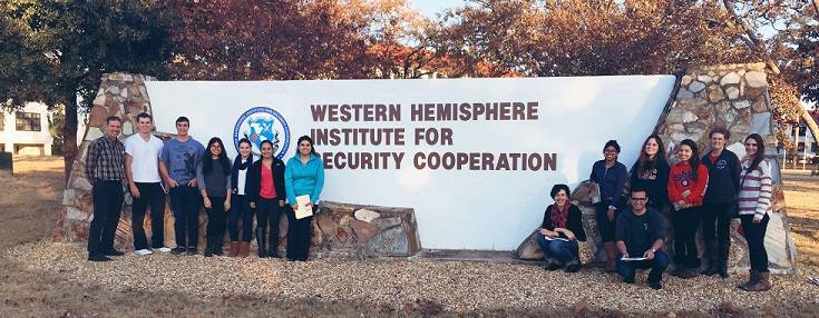 group of 14 people standing in front of the Western Hemisphere Institute for Security Cooperation sign