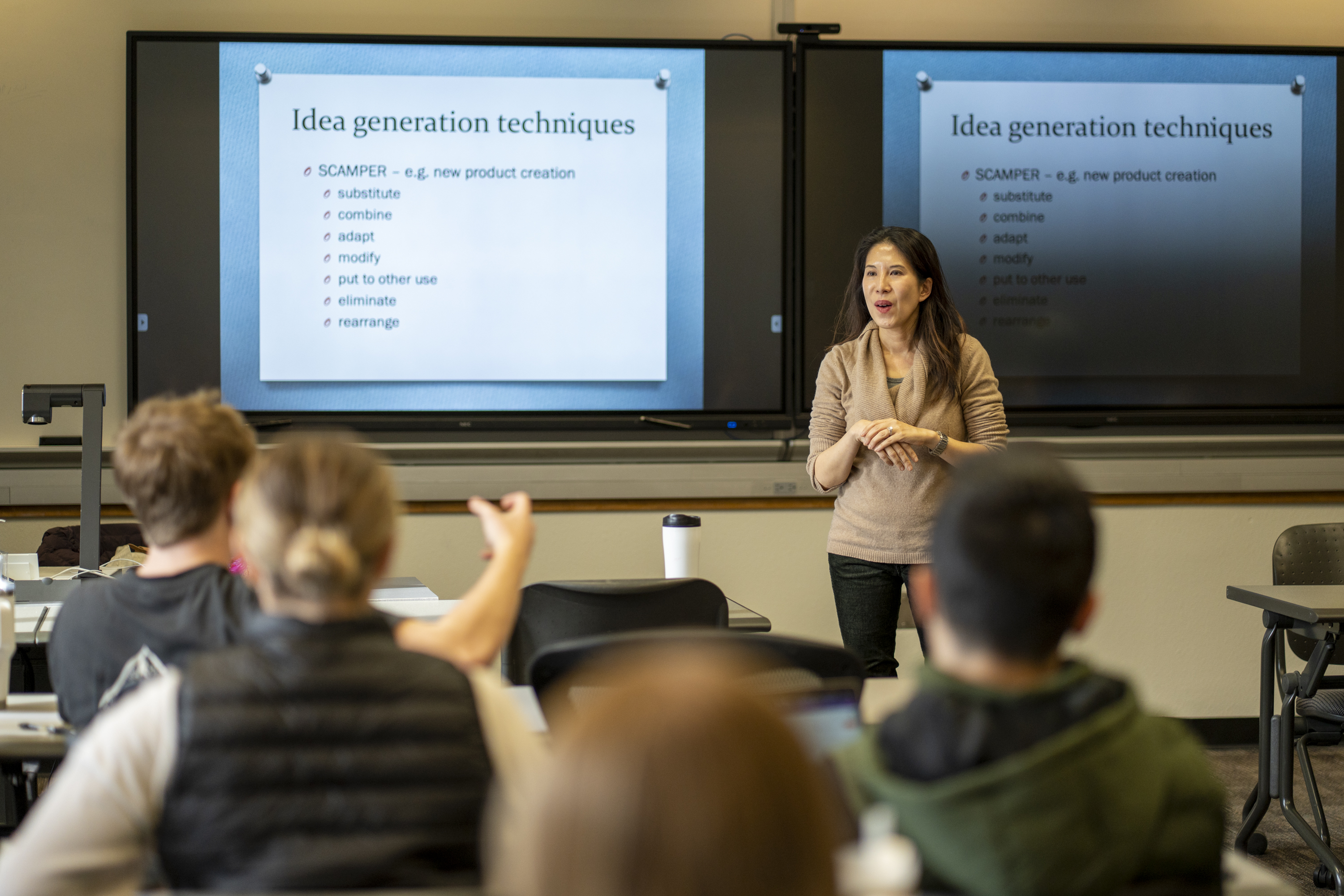 Professor Nancy Lam speaking to her JAN 101 - Turning On the Light Bulb: Illuminating, Unleashing and Managing Creativity course. On the screen behind her is a slide titled "Idea Generation Techniques"