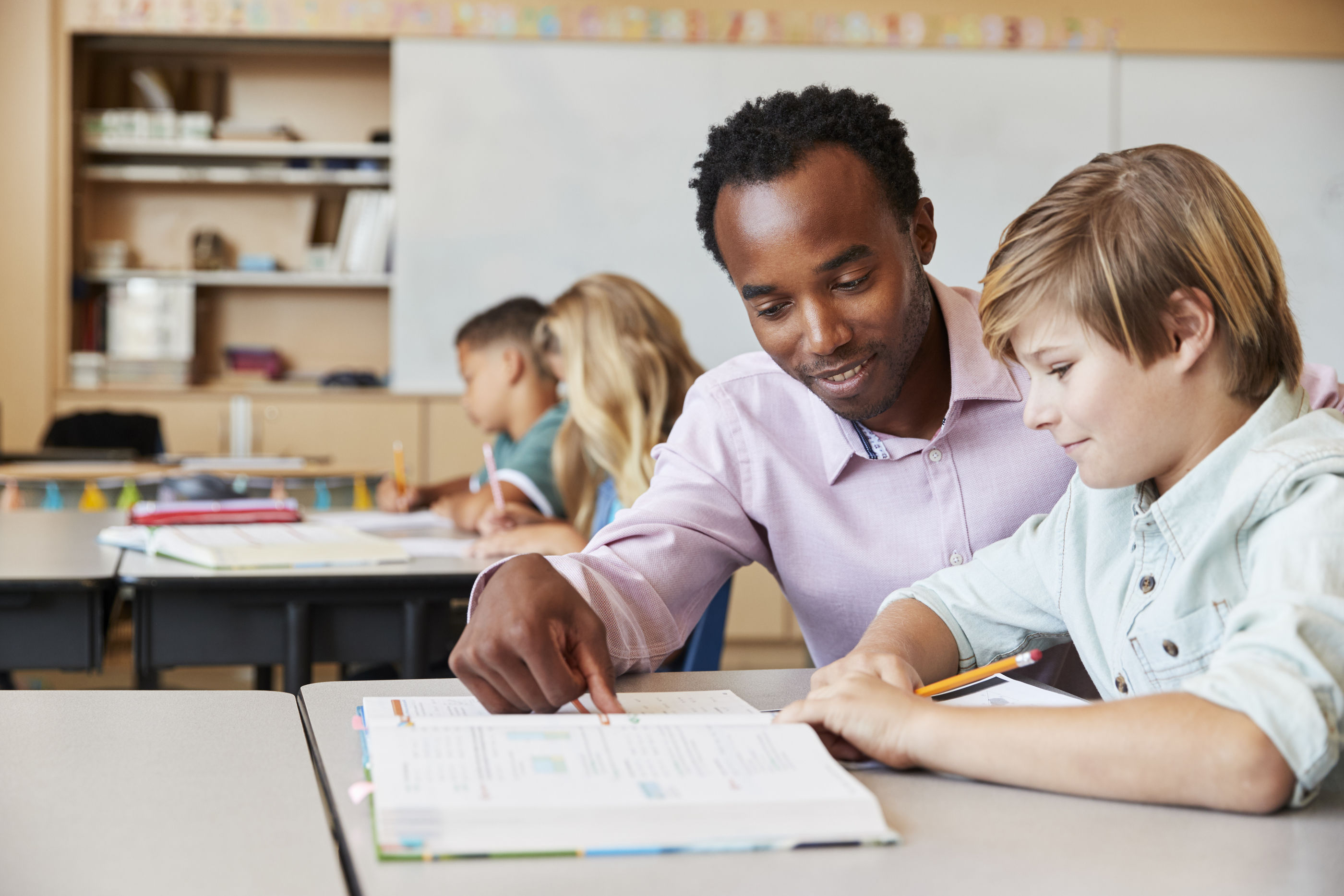 Male teacher teaching a student in the classroom