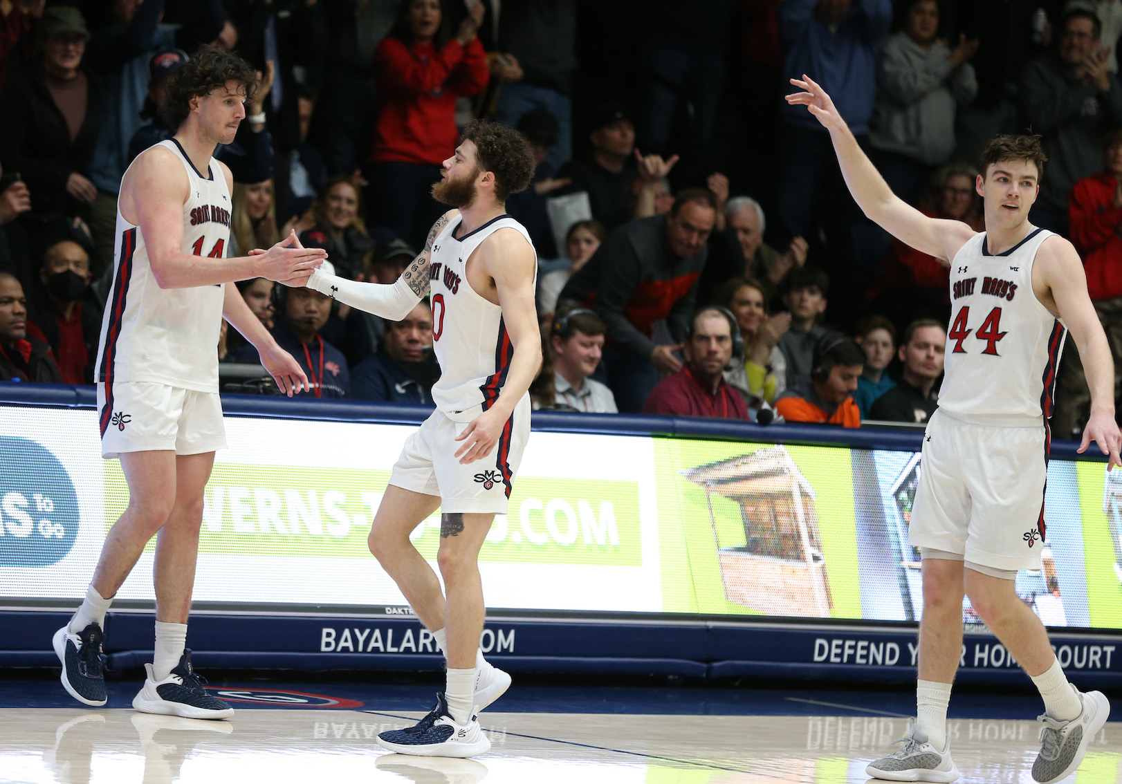 Three men's basketball players celebrating on February 23, 2023