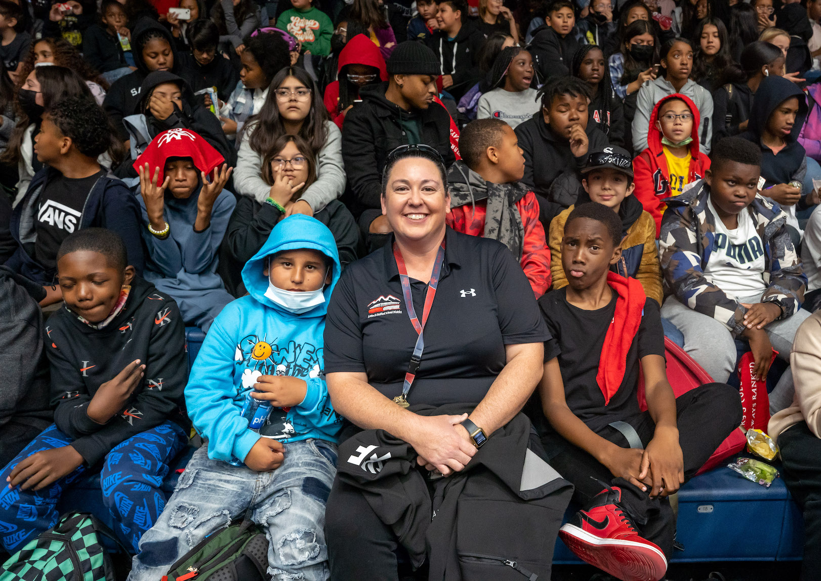 Lindsay Lopez-Wisely '04 sits amongst middle school students at a basketball game