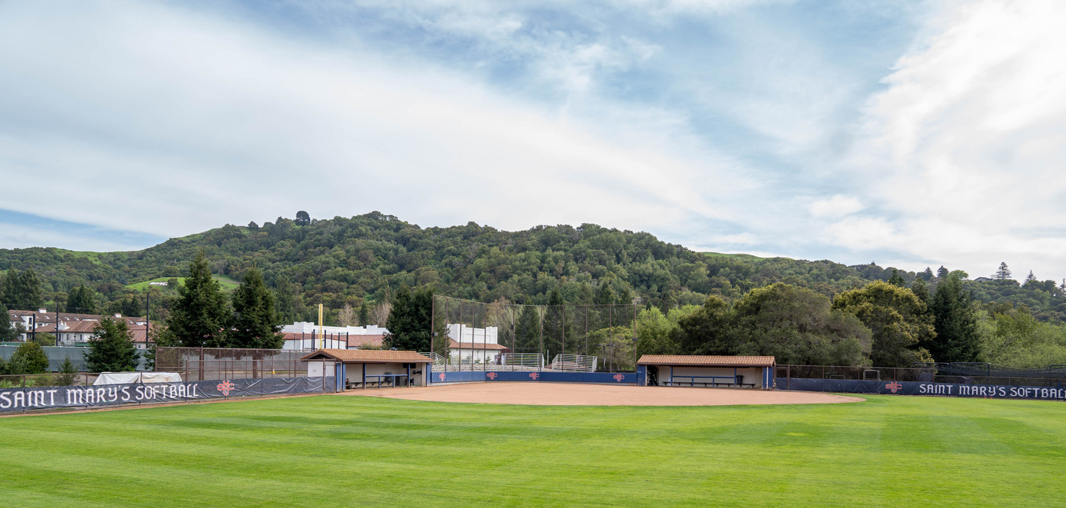 softball field with green grass and hills behind