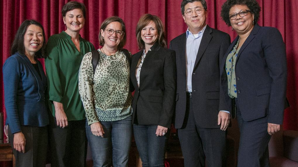 six people in front of red curtain