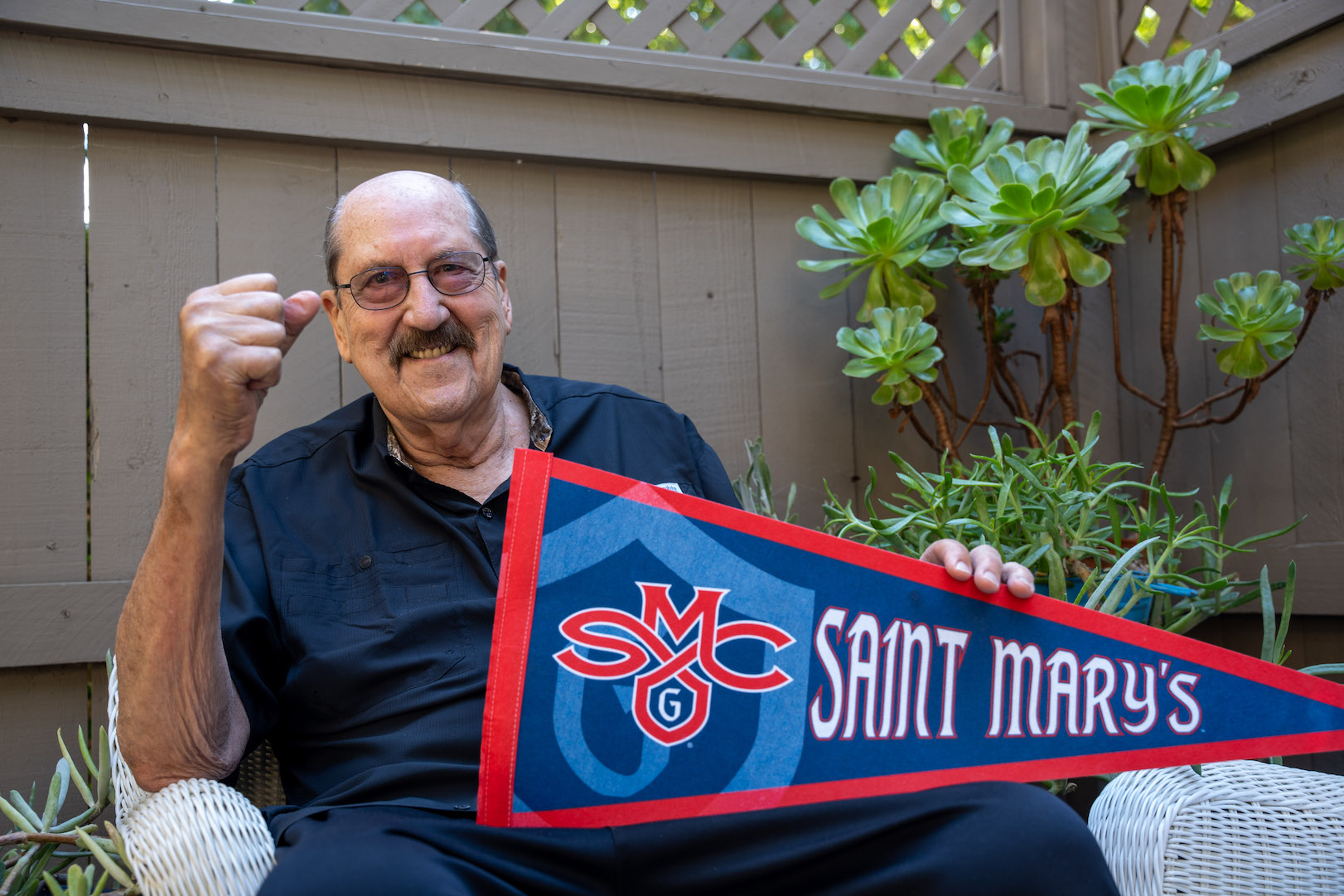 Tom Meschery holds an SMC pennant on his patio