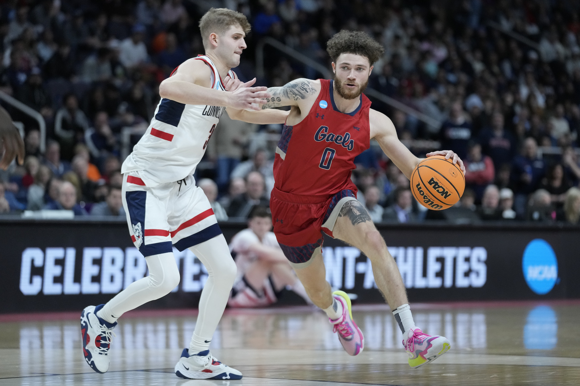 SMC basketball player Logan Johnson drives against a University of Connecticut player in NCAA tournament on March 19, 2023