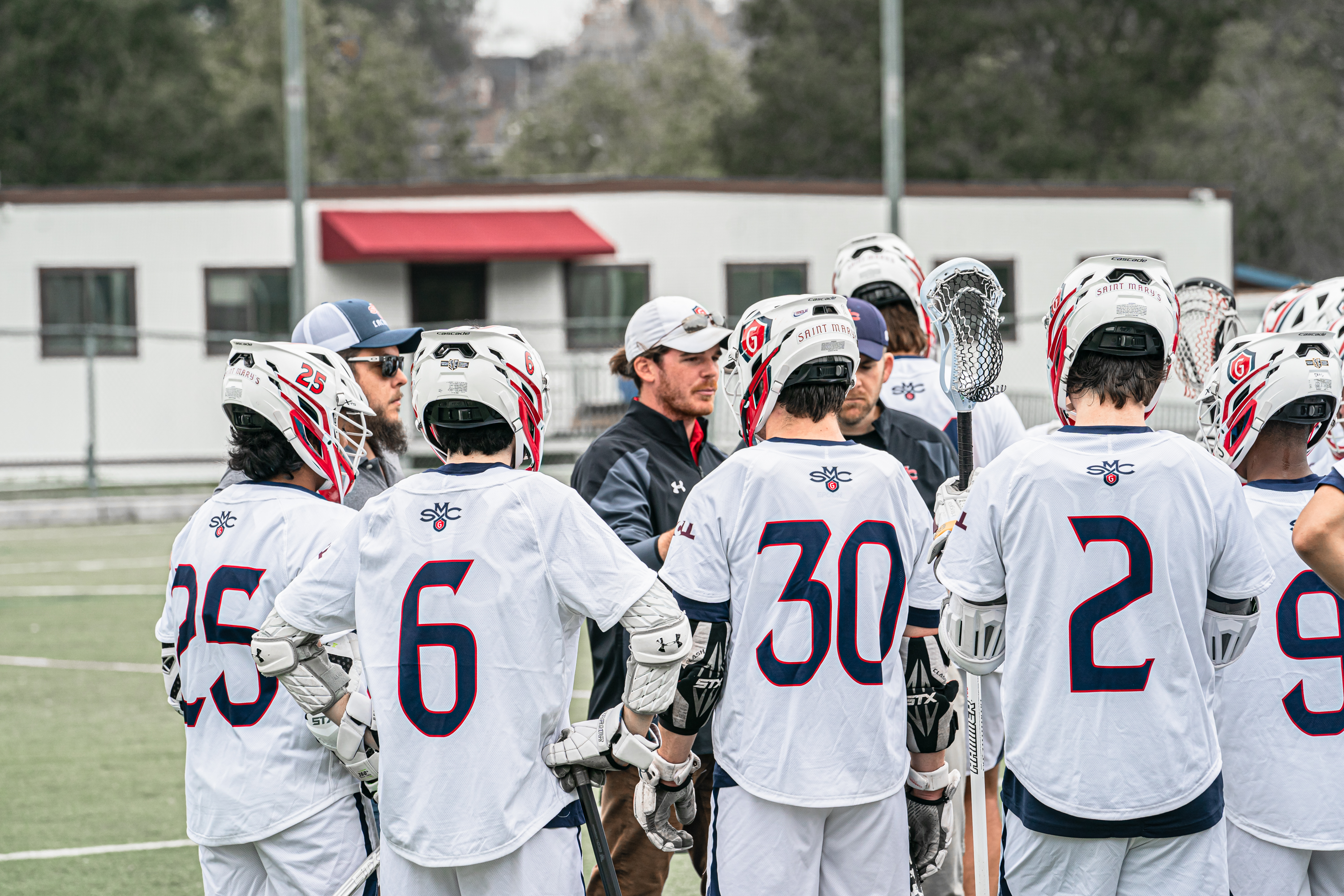 Men's Lacrosse Players huddles around for coach talk