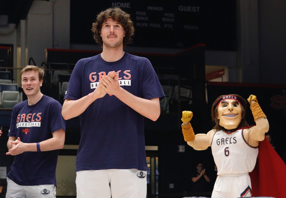 Two men's basketball players and mascot Gideon celebrate March 12 2023 NCAA bid announcement