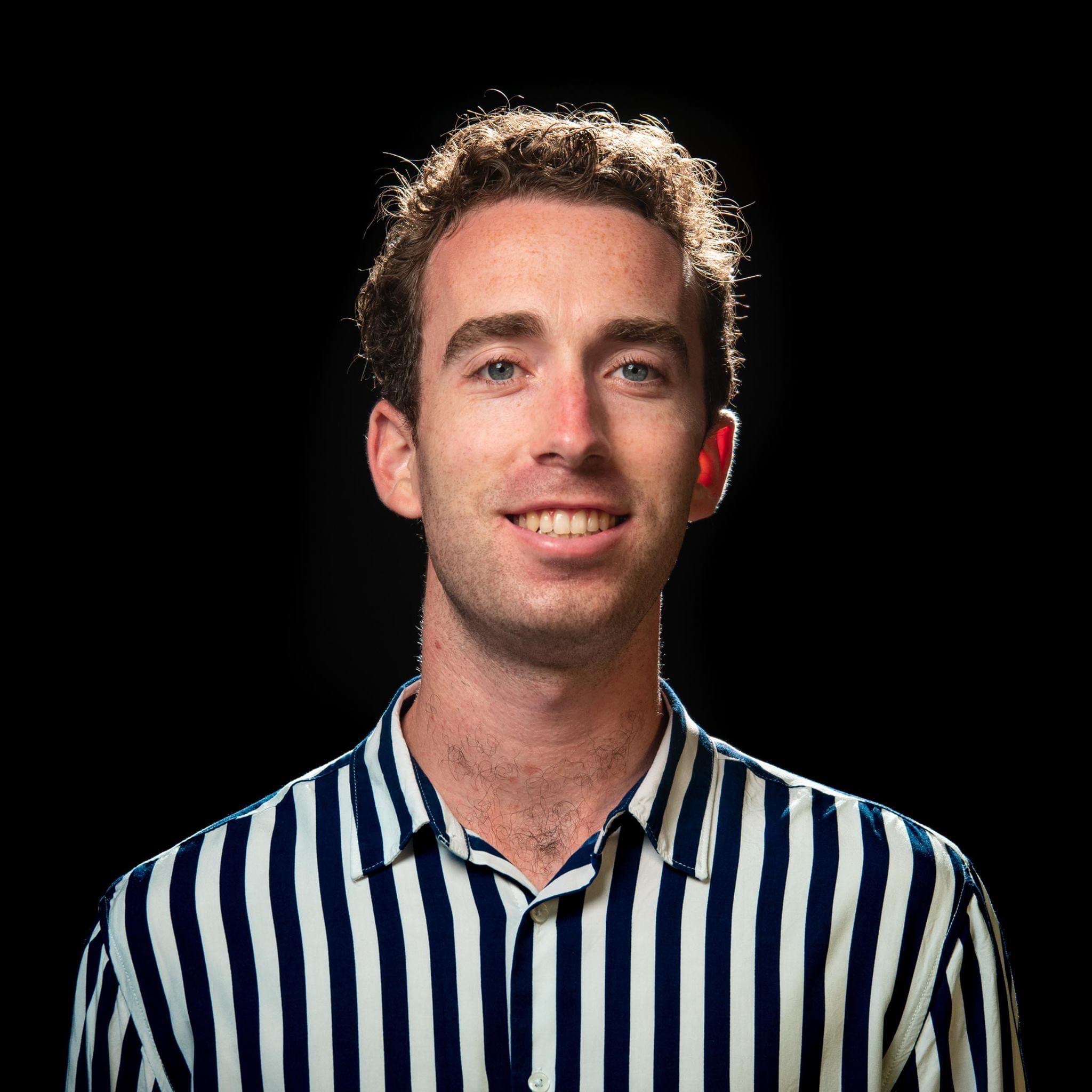 Michael Blackburn in a striped shirt against a black background