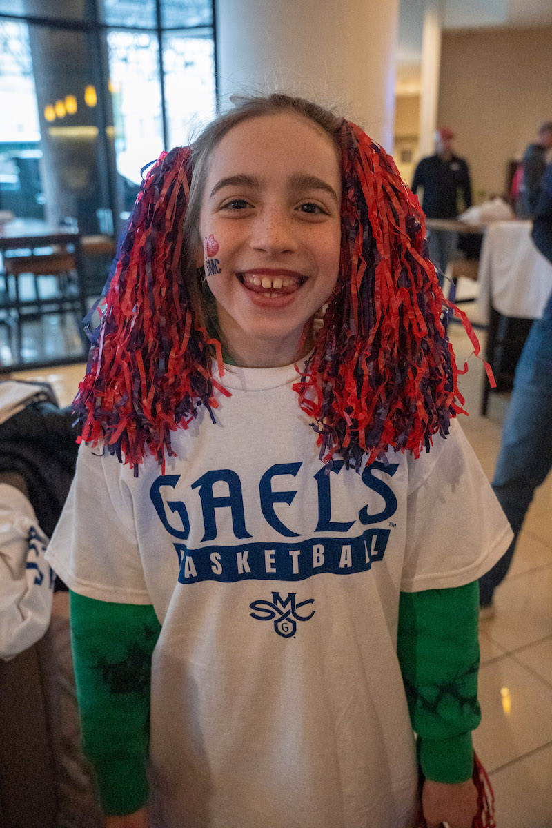 A school-aged girl wears red and blue pom poms in her hair