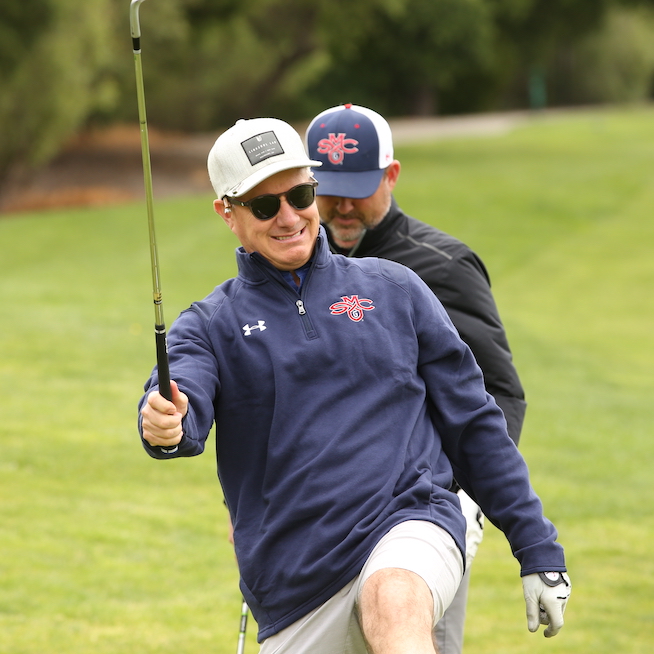 A golfer smiles and gestures