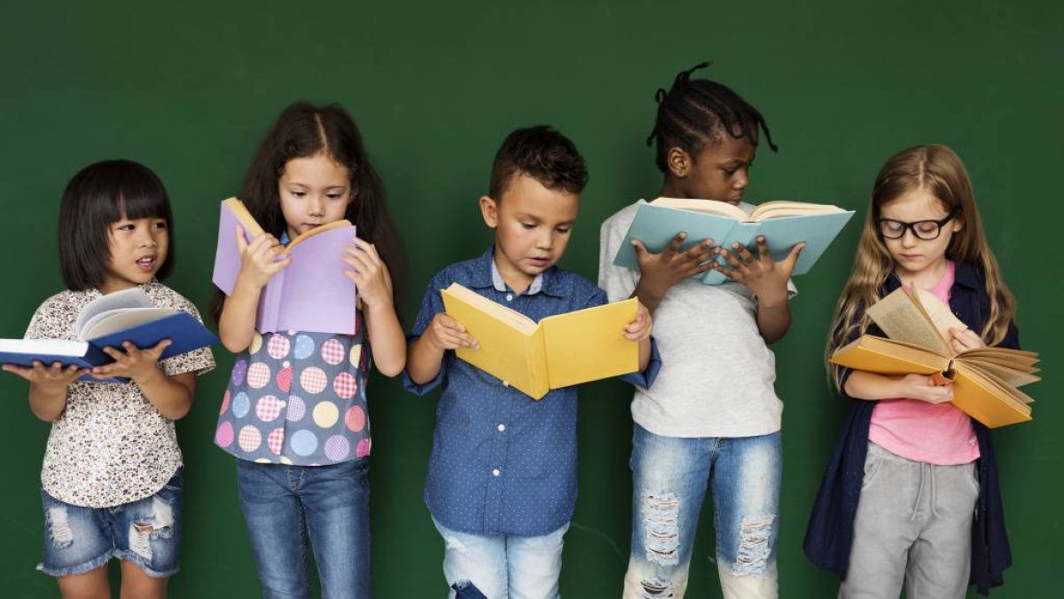Five children standing next to each other, all reading books