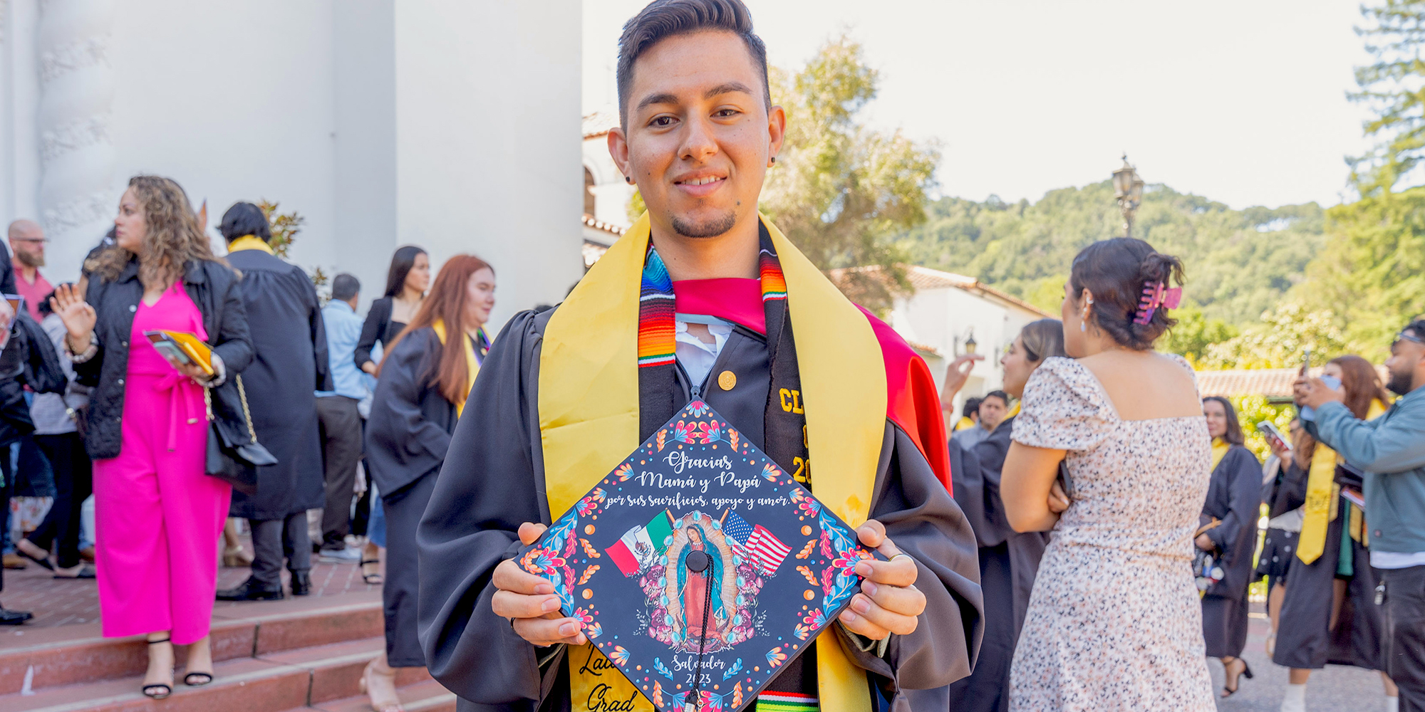 Student holding mortarboard with image of Virgen de Guadalupe at Latinx Graduate Celebration 2023