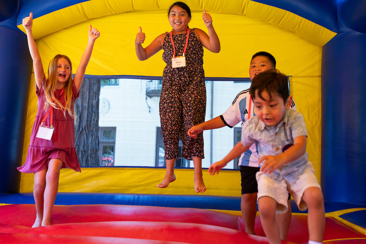 Four young kids jump in a bounce house during Reunion 2023