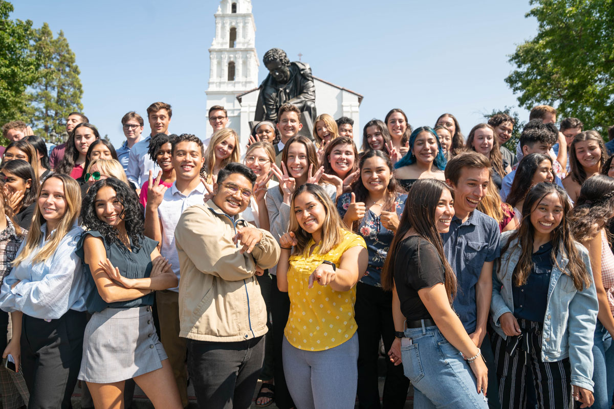 Students in a group smiling in front of the saint mary's college campus