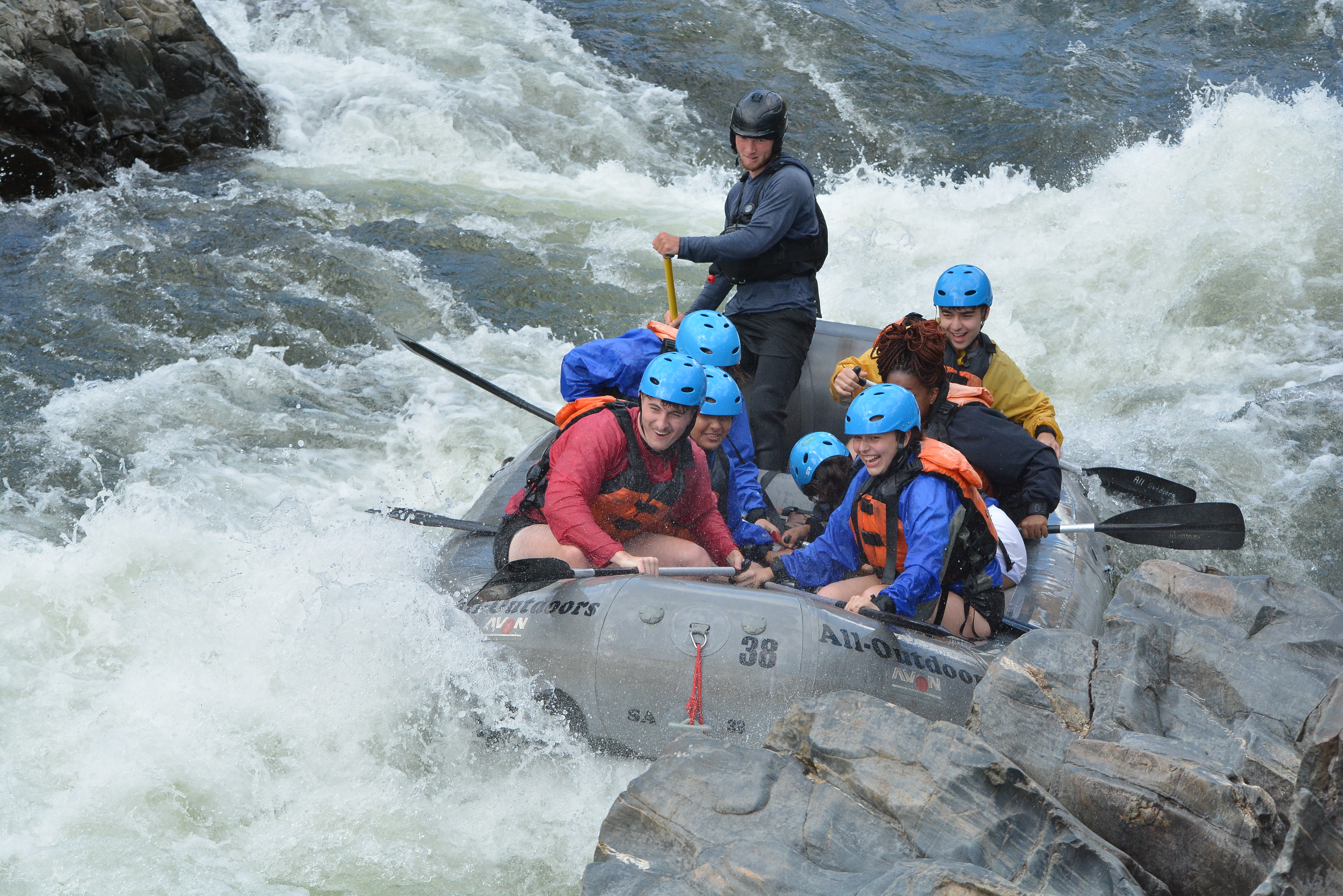 Students in rafting boat going down a rapid