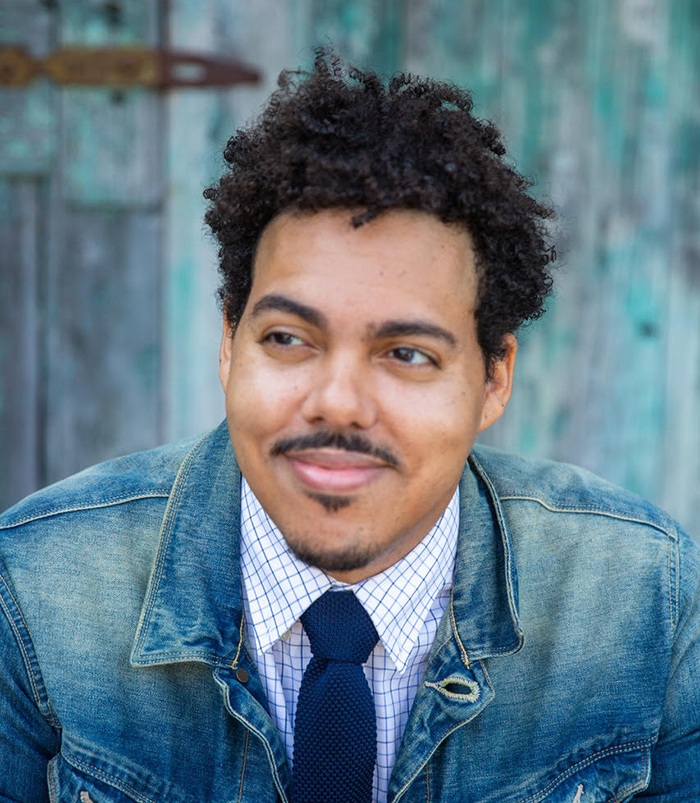Headshot of Visiting Writer Jonathan Escoffery with denim and a blue background.