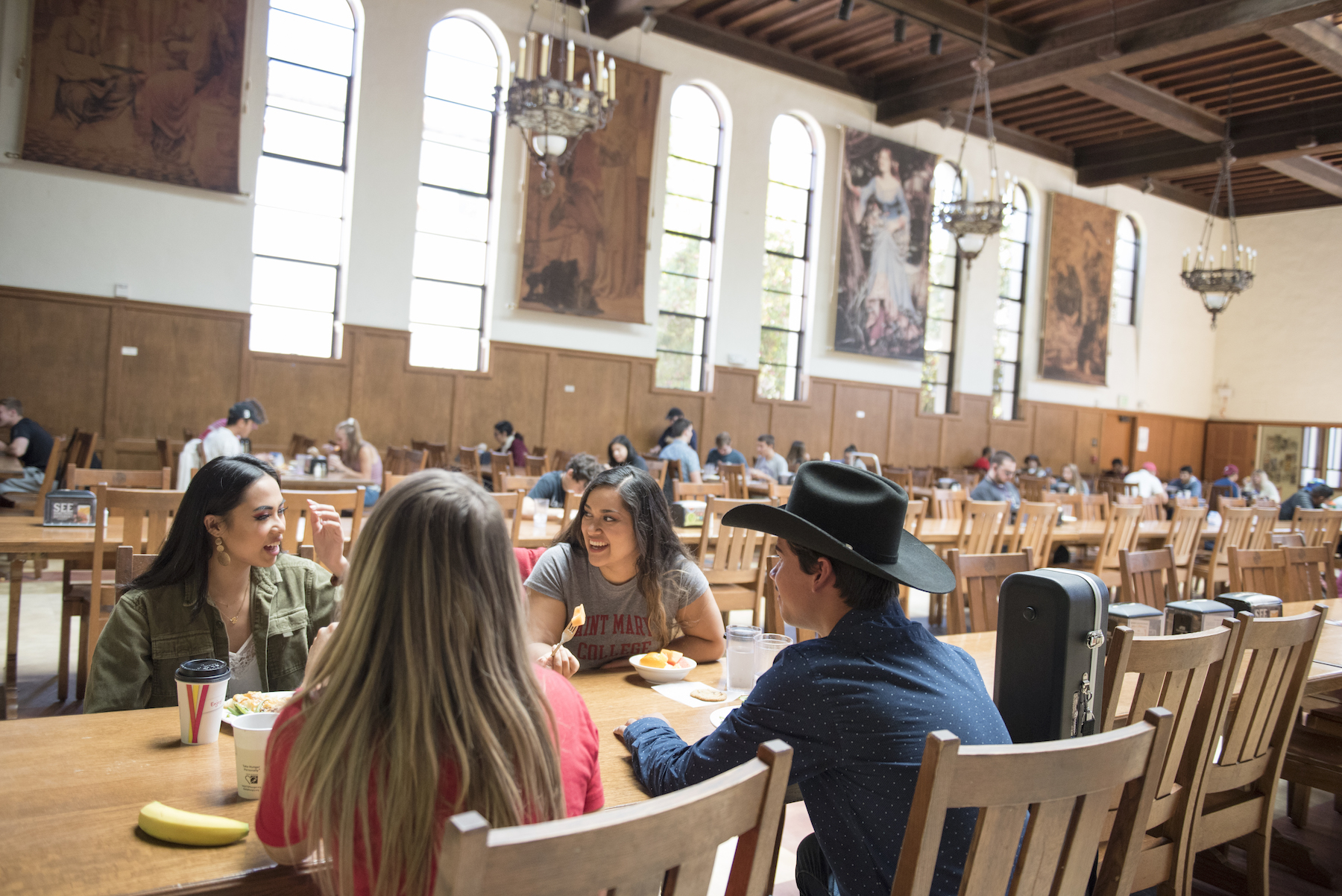 Four students sit at a long dining table in Oliver Hall