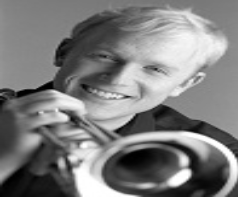 A black-and-white headshot of Scott Macomber holding a trumpet