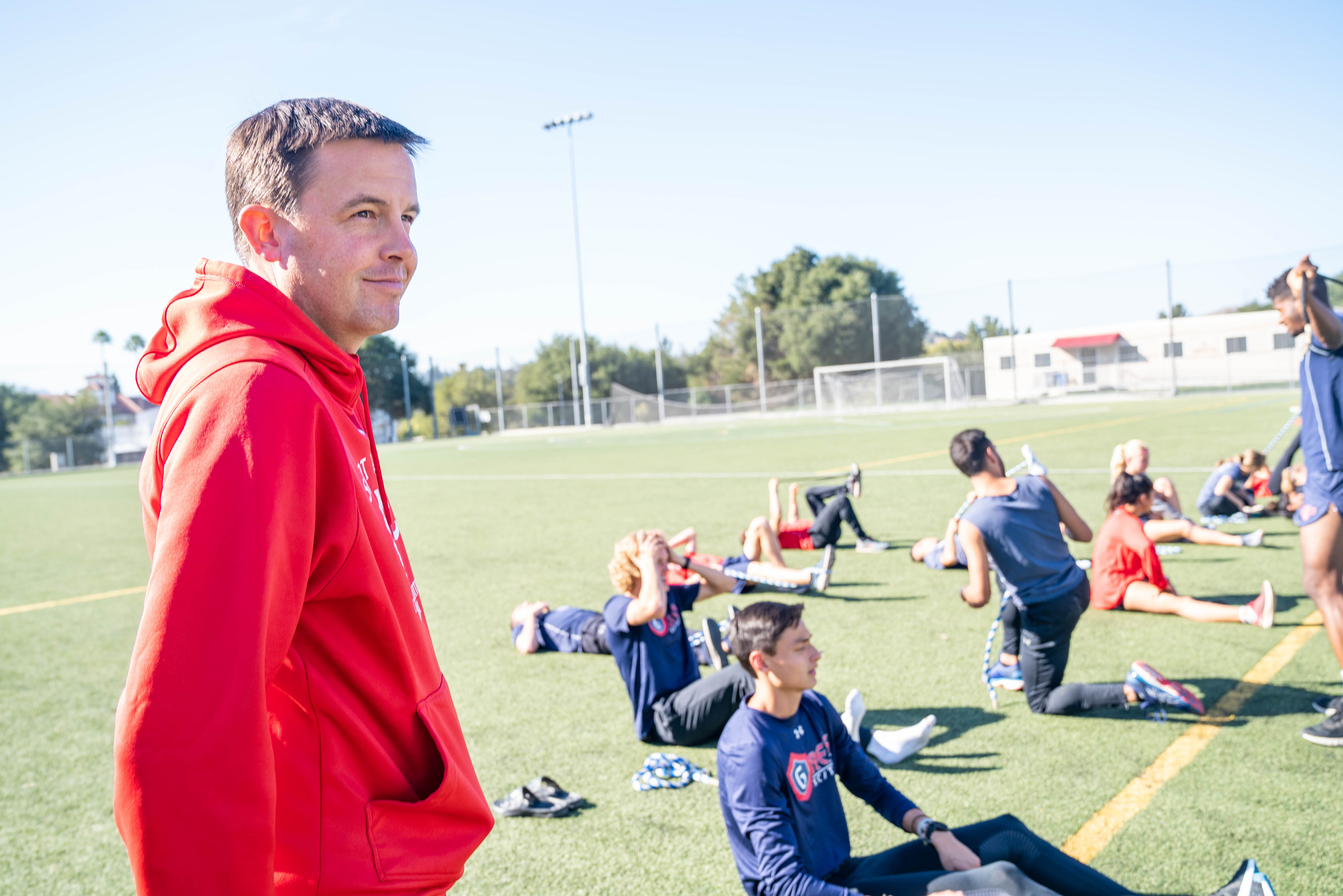 Marty Kinsey at practice, while student-athletes stretch