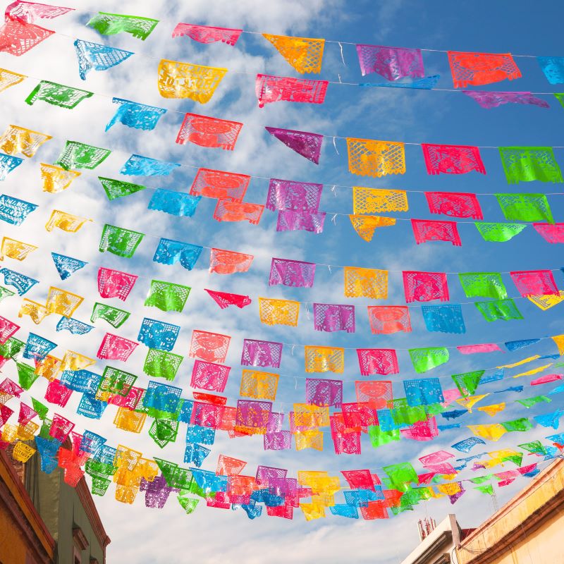 colorful papel picado garlands under a blue sky