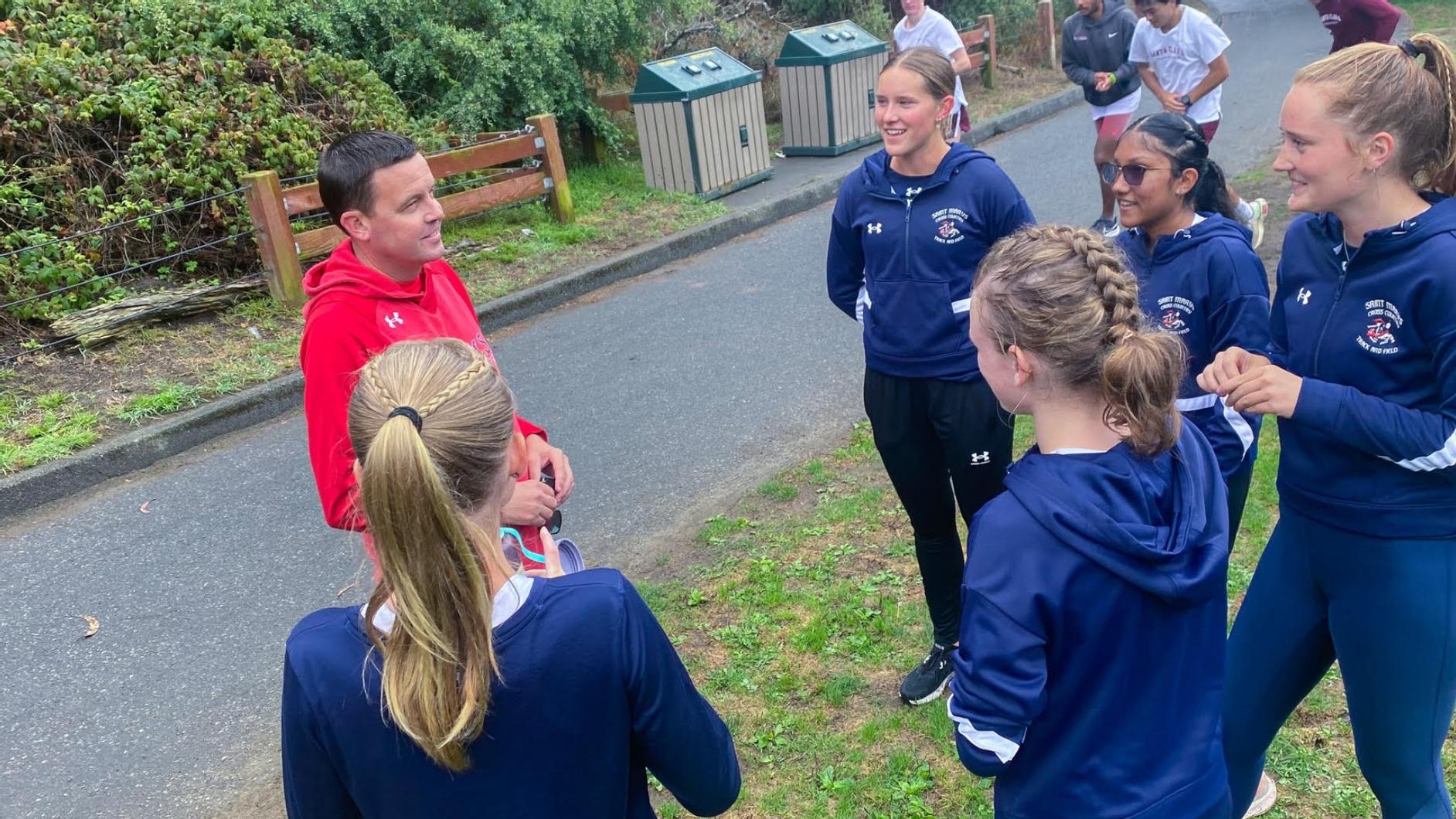 Women's cross country coach Marty Kinsey with five women runners, 2023