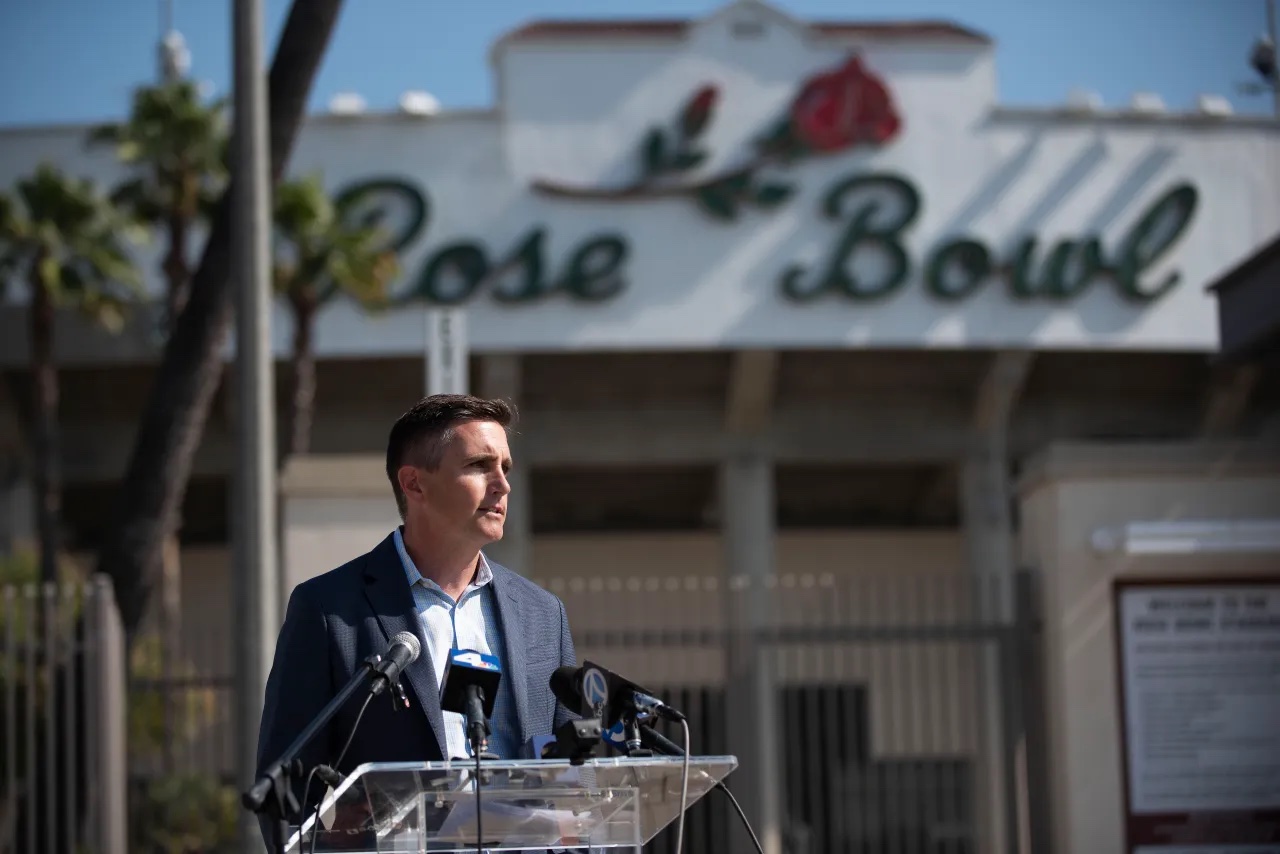 Jens Weiden speaks at a podium with the Rose Bowl stadium and logo in background