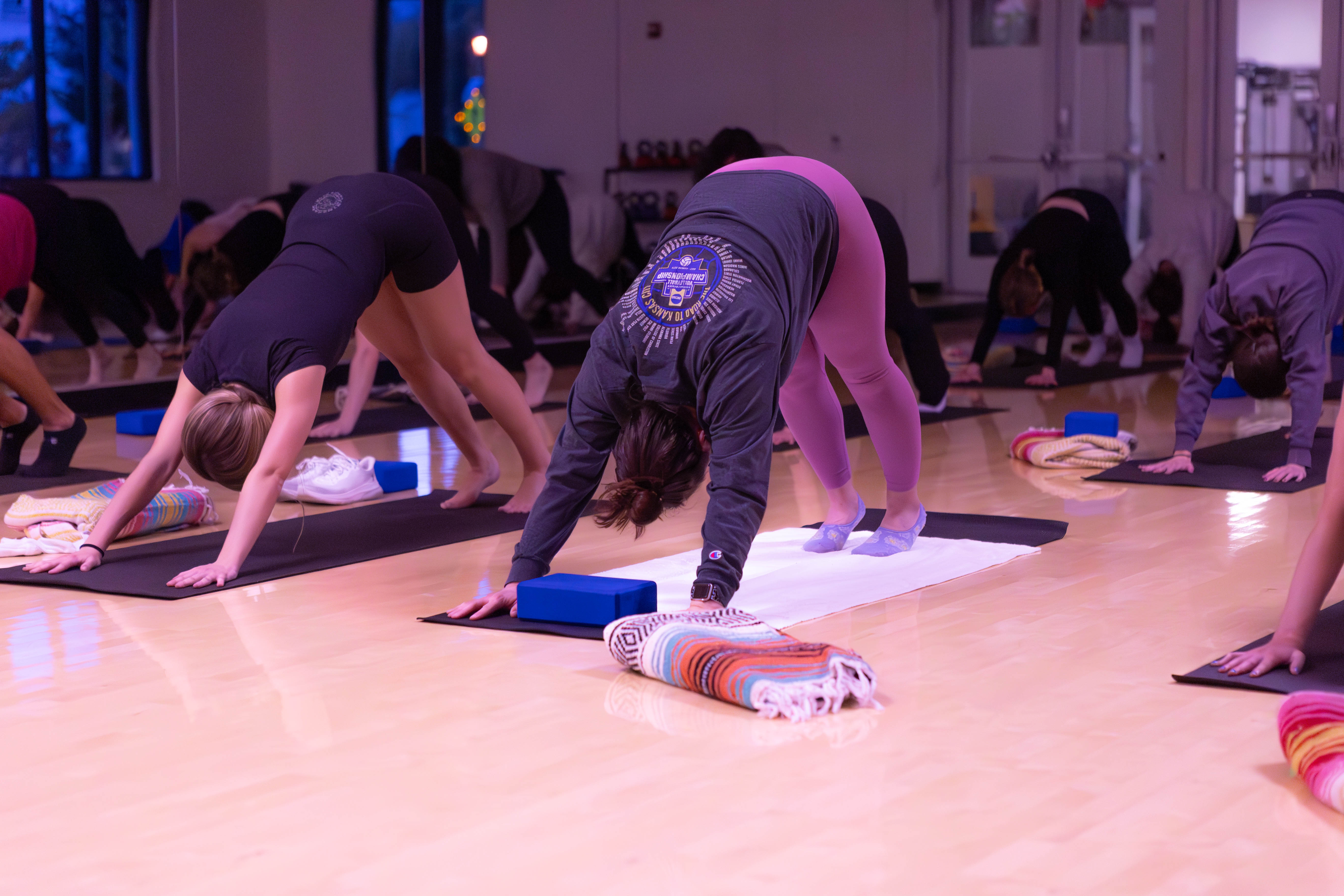 STRETCH: Yoga attendees stretch in downward dog position during the fitness class on Feb 14 as part of the LoveWell event to promote self care. / Photo by Rebecca Harper