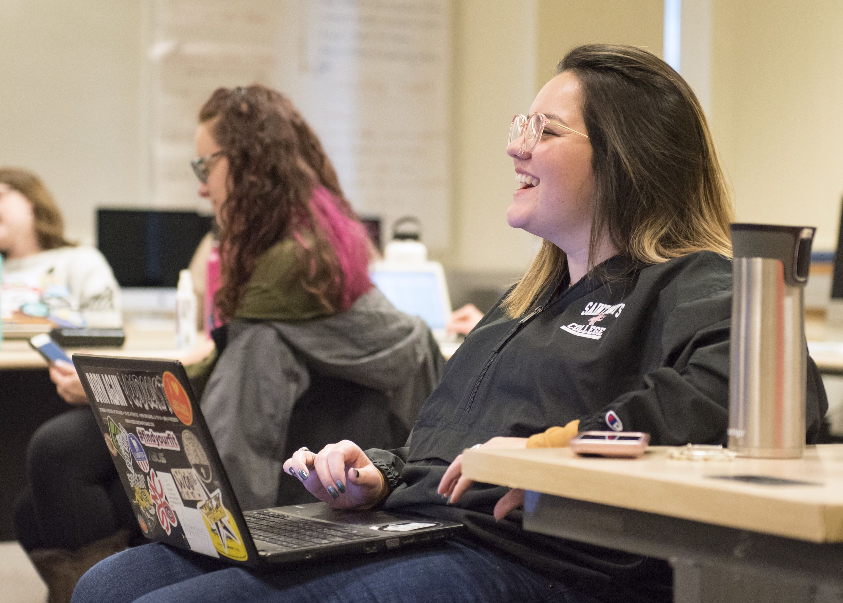 Woman laughs while using her computer in a classroom