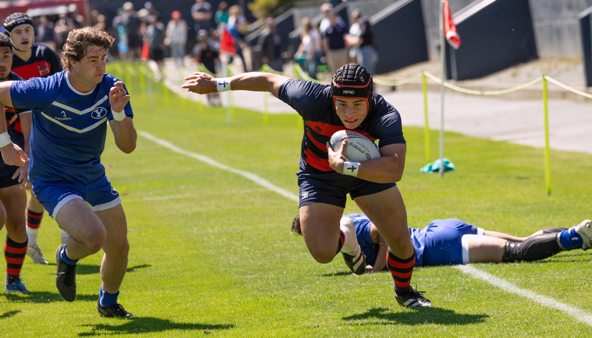 SMC Men's Rugby player runs with the ball past BYU defenders, April 2024