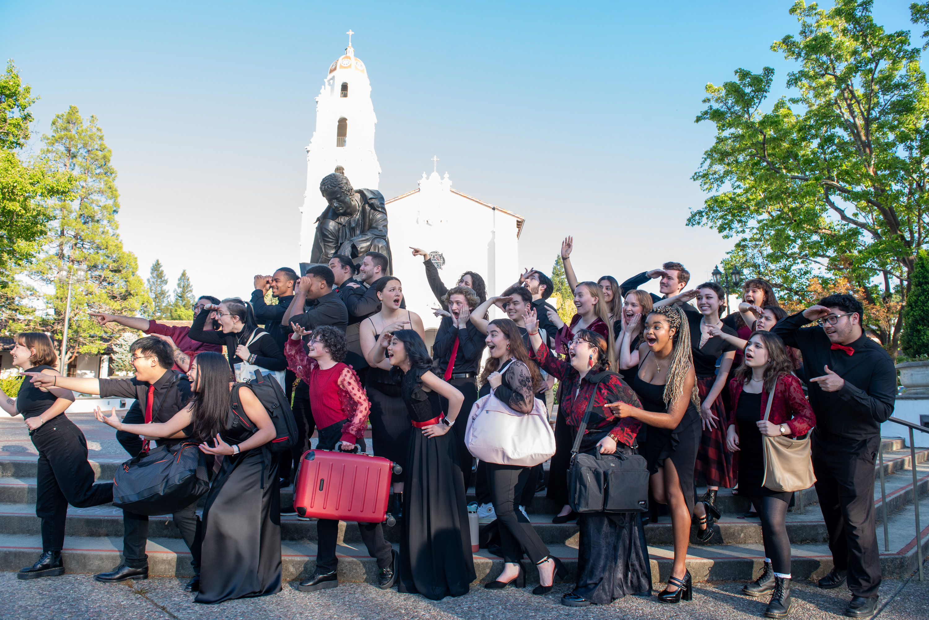 2024 Choir Photo in front of De La Salle statue, holding suitcases and looking towards the left