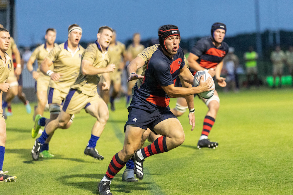 Rugby player Dominic Besag runs while Navy defenders chase him in 2024 national championship