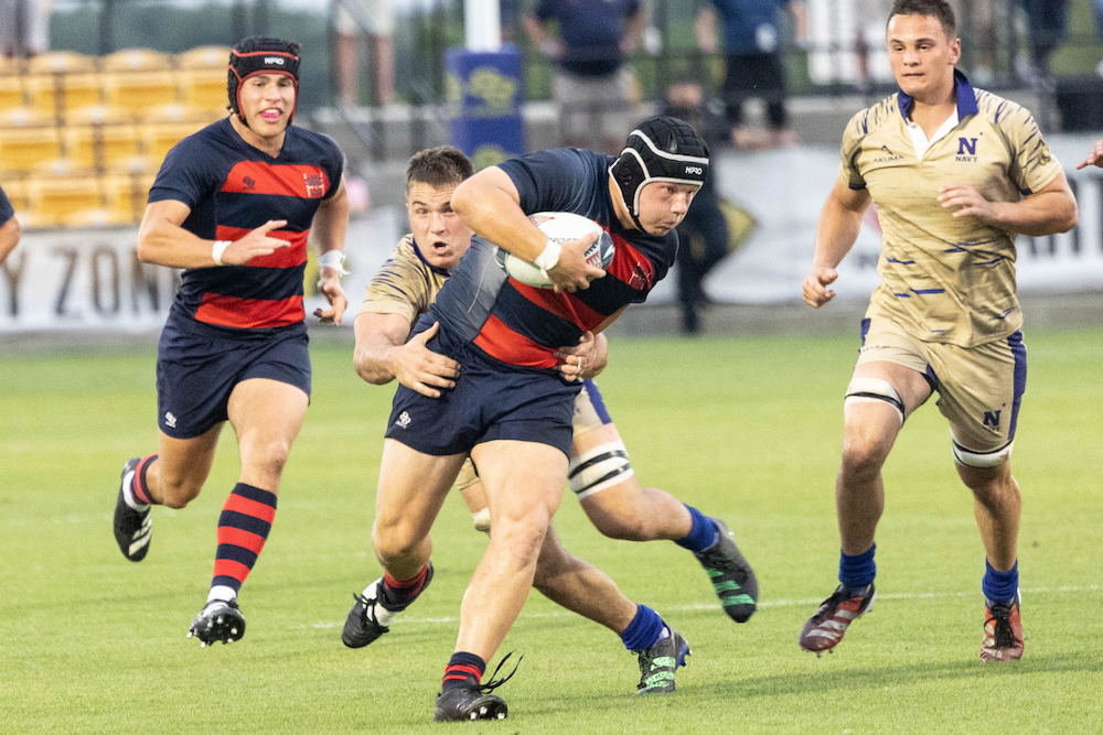 Men's rugby player John Battle Wilson runs with the ball while a Navy defender tries to tackle him in 2024 National Championship