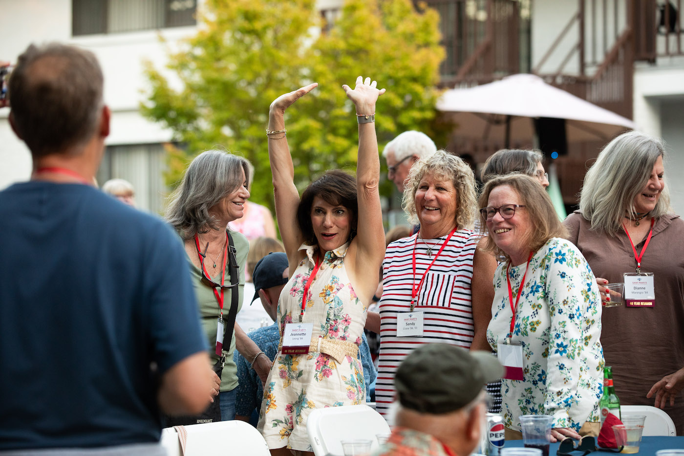 Jeanette Leong '84 holds her hands in the air to greet a friend at Reunion