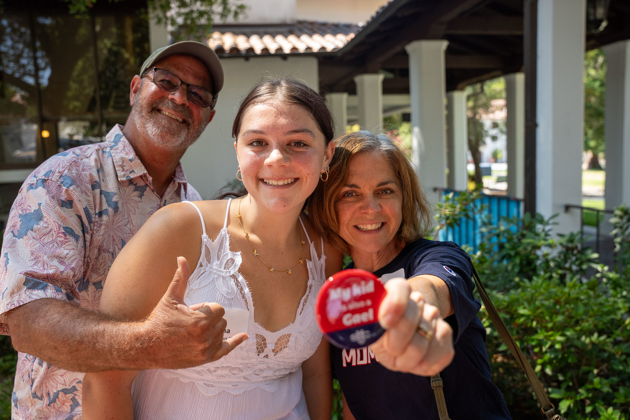 A student is held close by her parents while her mom holds a button reading: My kid is also a Gael