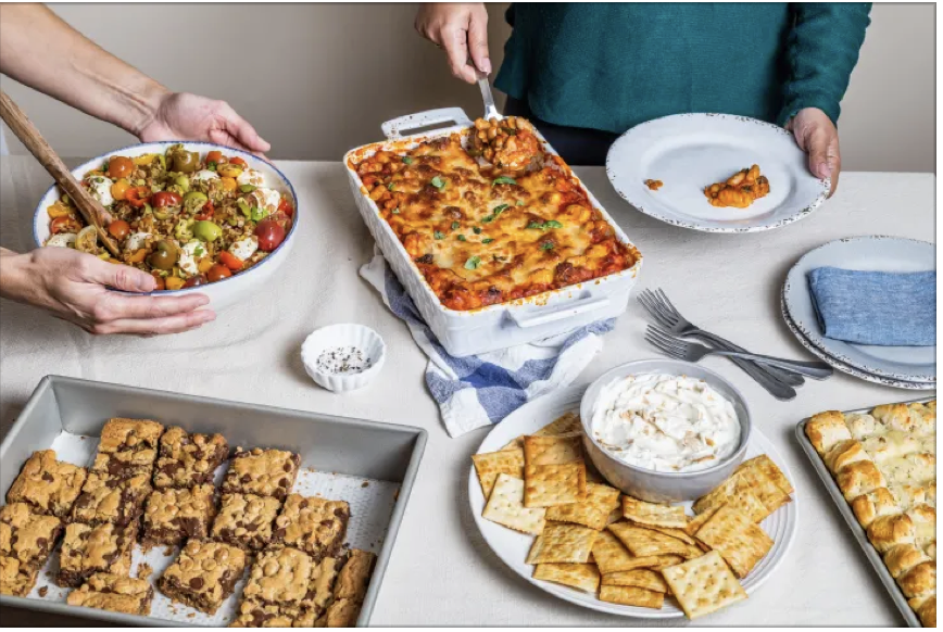 Potluck including cookies, casseroles and crackers and dip.