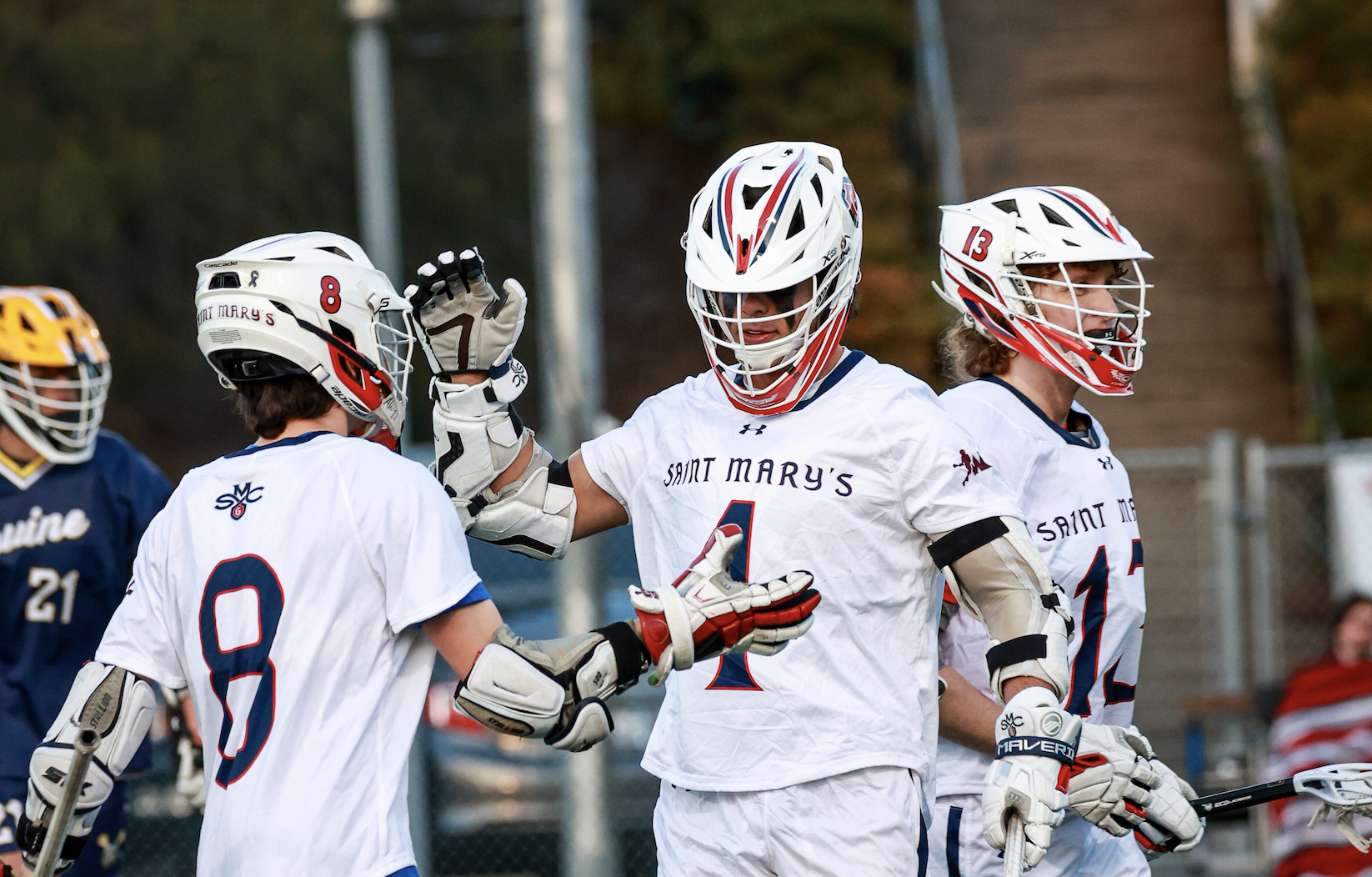 Men’s Lacrosse team members Tim Daly (No. 8), Dario Caccia (No. 4), and Hayden Bradley (No. 13) celebrate after scoring against UC Irvine in a match on the Recreational Turf Field last Spring. / Photo by Ashleen Rai ’26