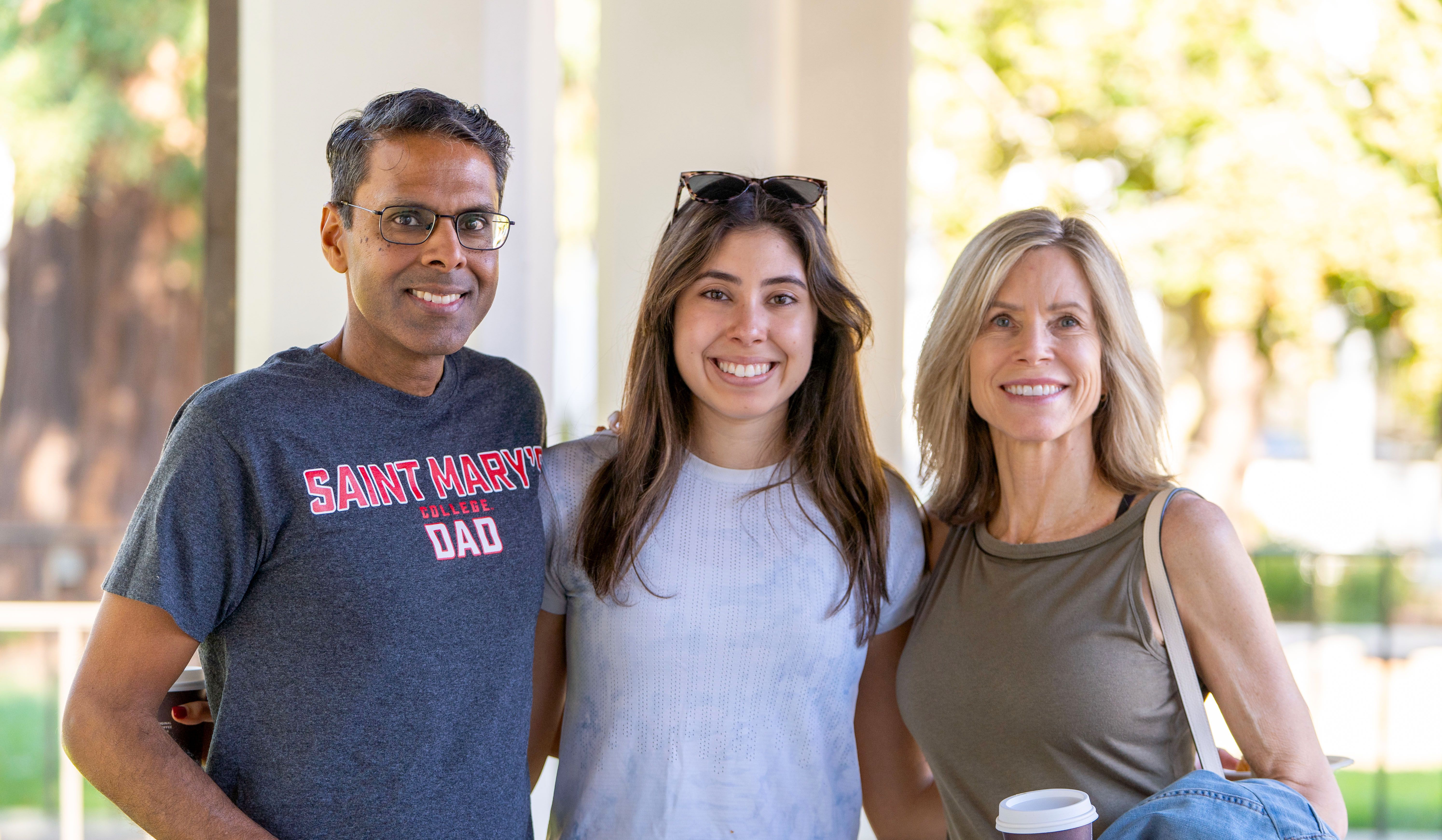 A student and her parents smile for a photo during Family Weekend