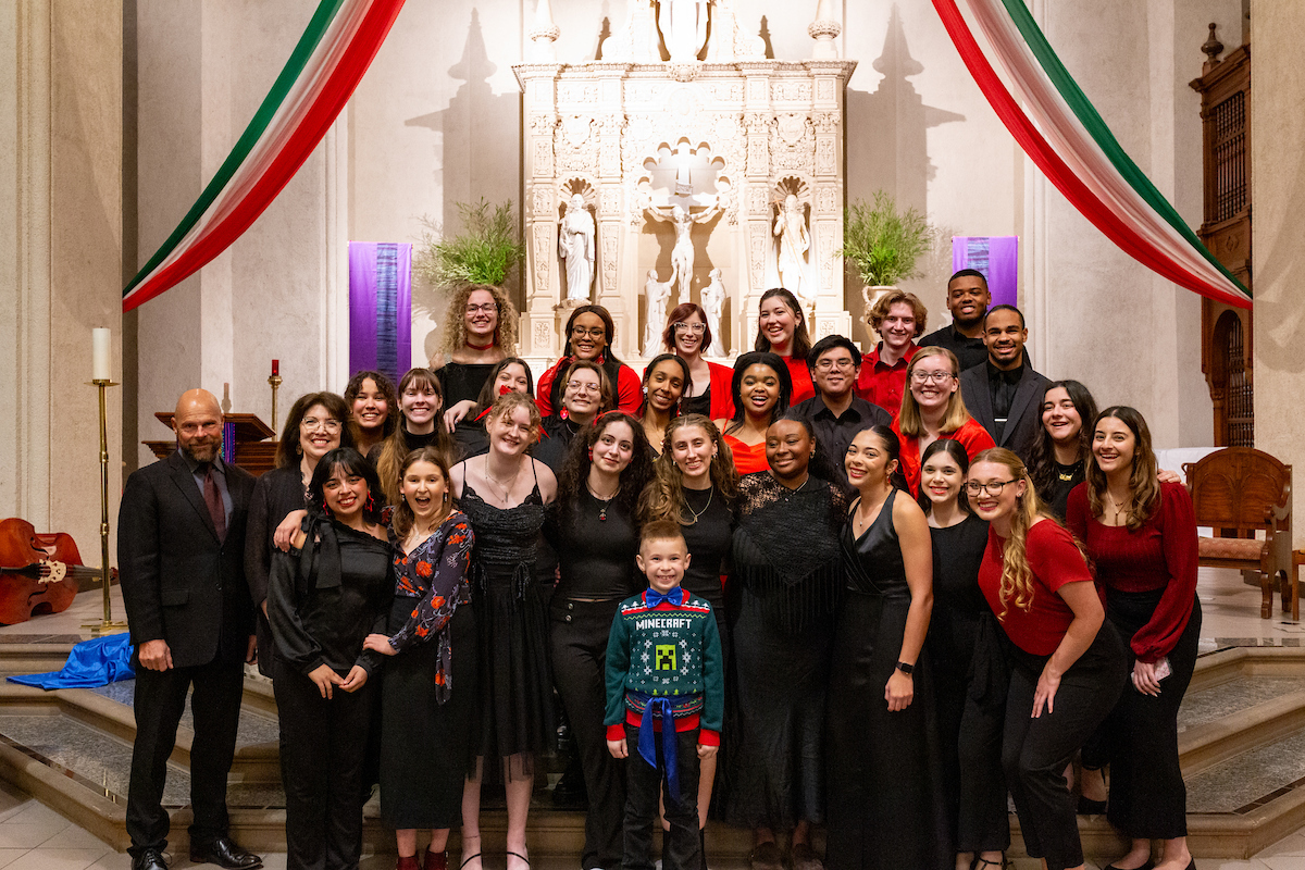 SMC Choir poses for a photo on the altar with formal black and red clothing on.