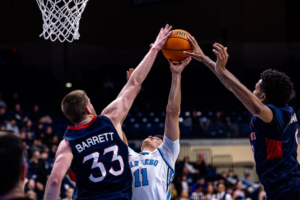 Men's basketball players Luke Barrett and Ashton Hardaway block a shot by a San Diego player in January 2025