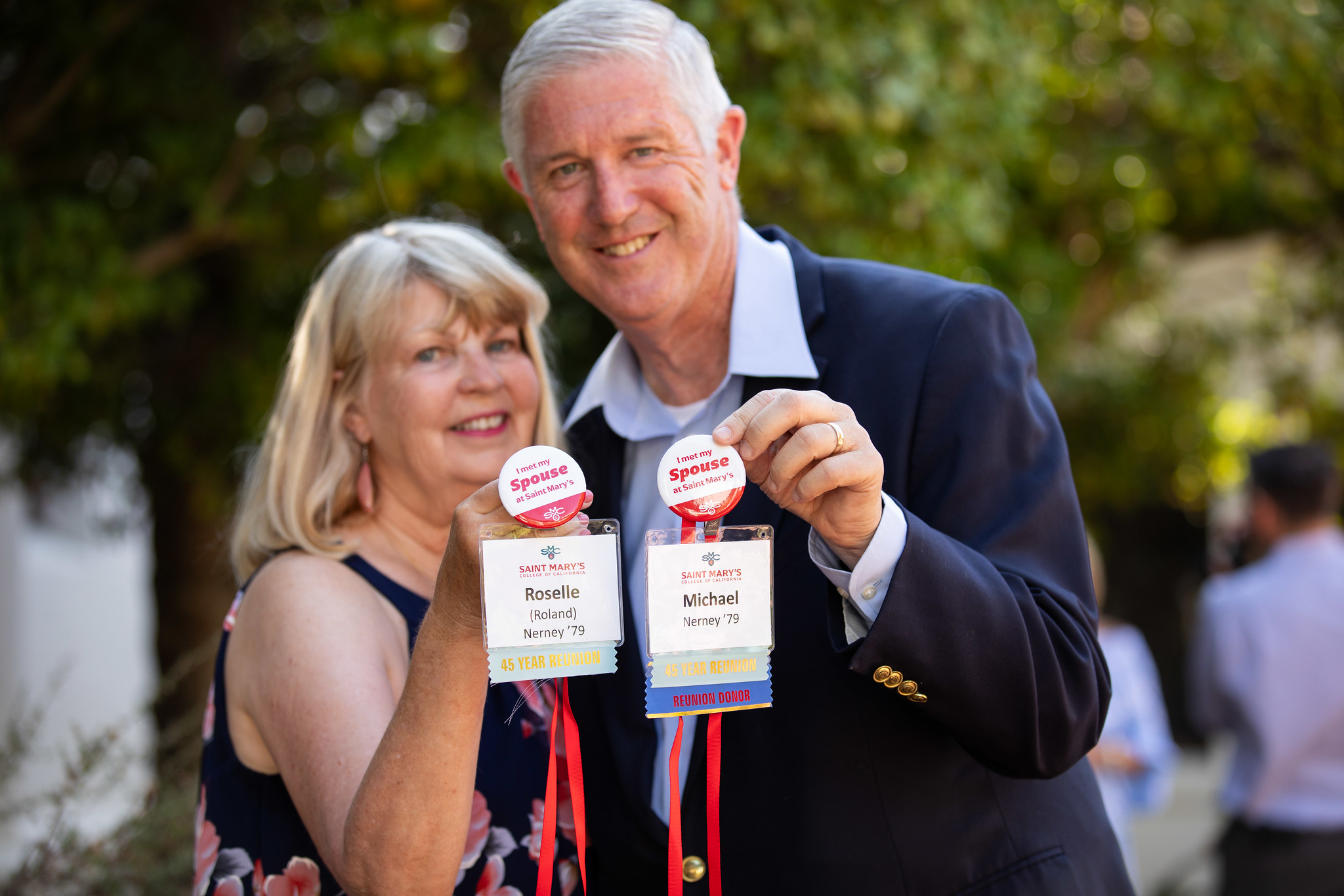 Roselle and Mike Nerney hold up their nametags with buttons reading "I met my spouse at Saint Mary's"