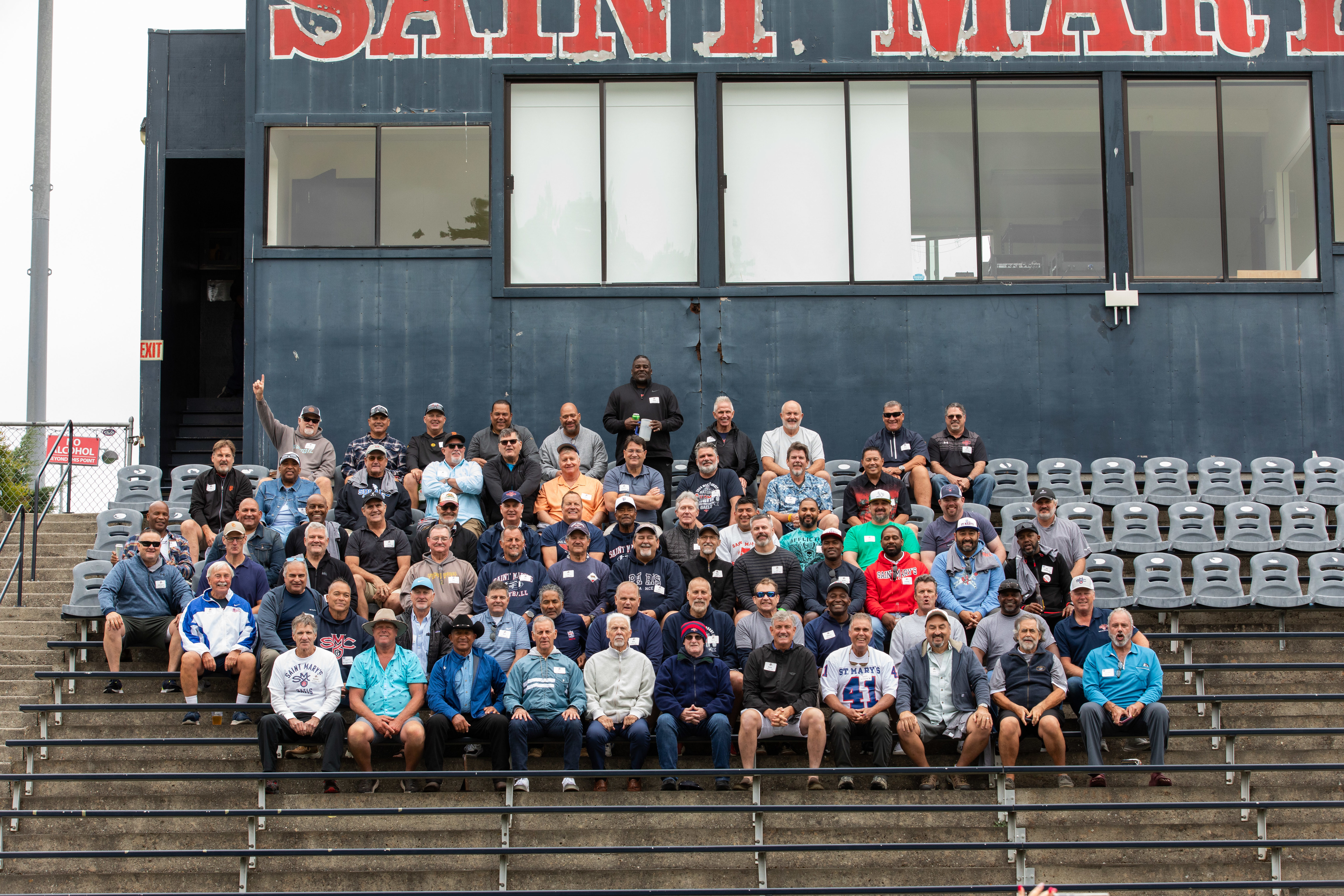Alumni sit in the bleachers to recreate a classic team photo